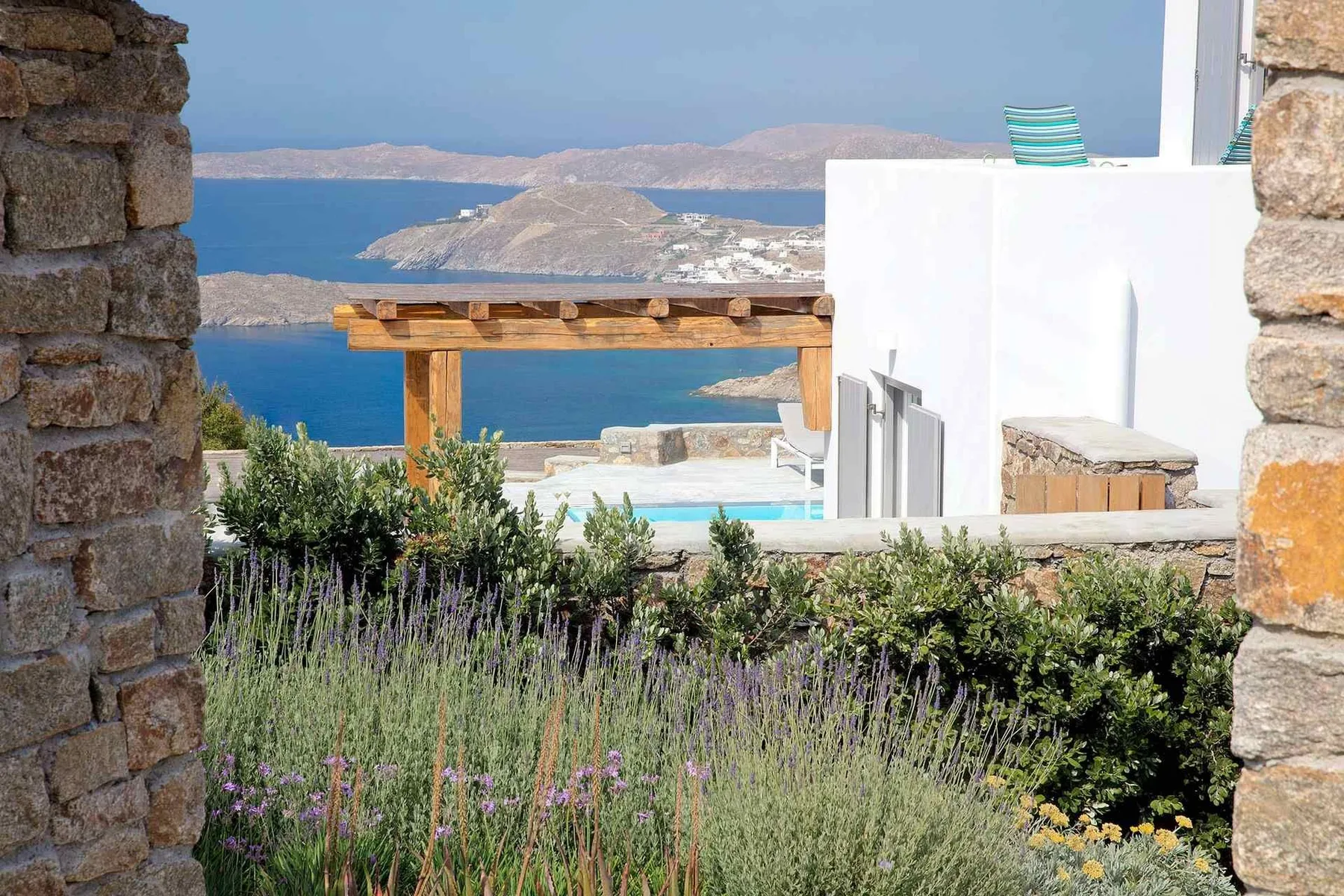 A coastal terrace overlooks the sea, with flowering plants in the foreground.