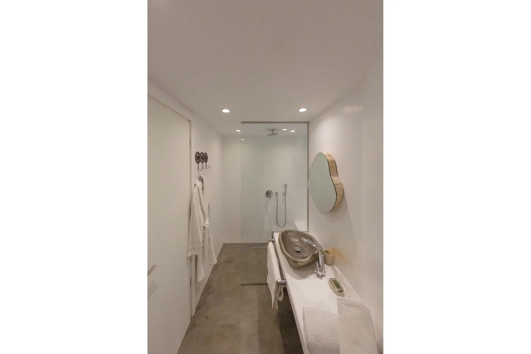 A bathroom with a walk-in shower, a sink, and a wall mirror.