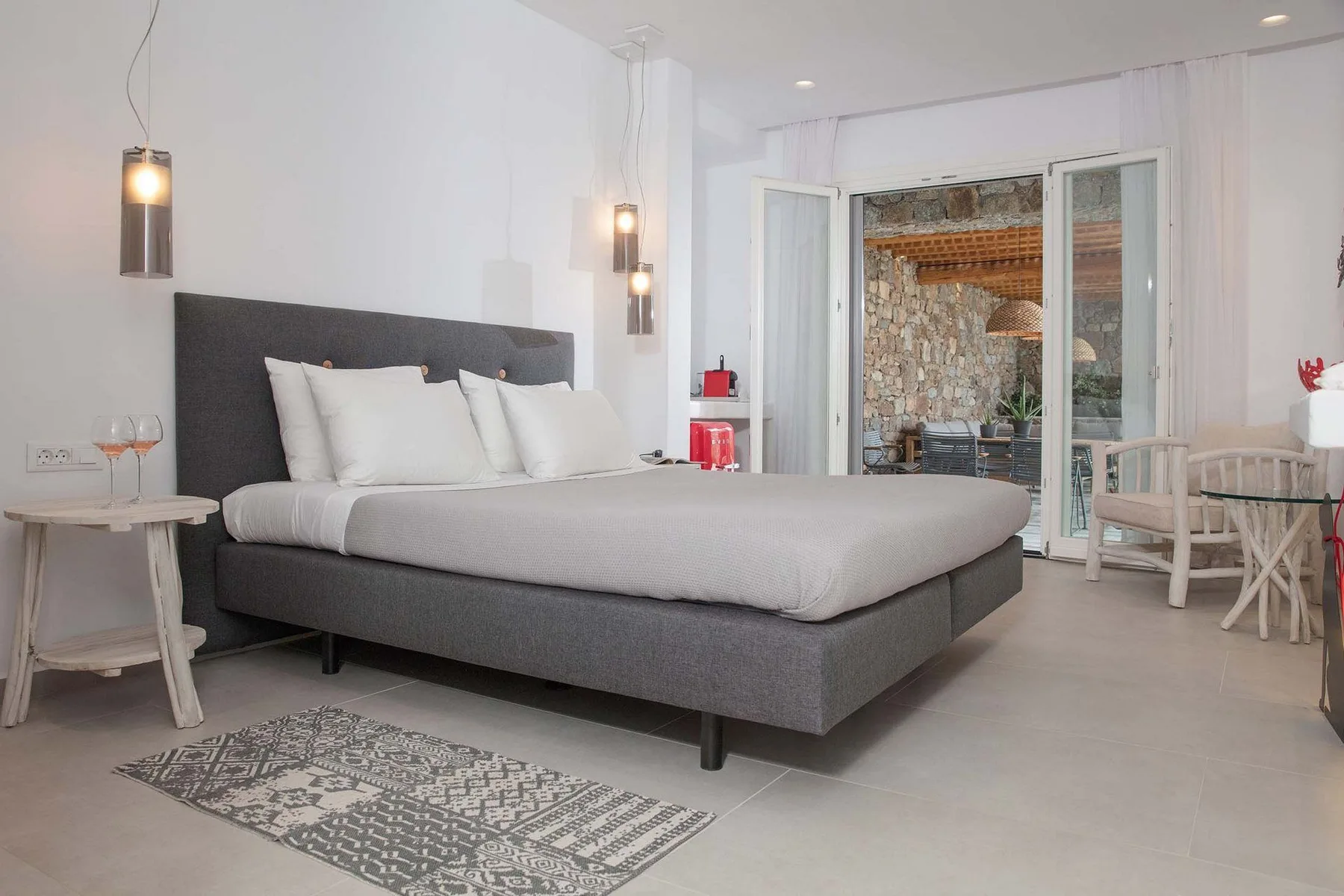 A bright bedroom with a large bed and glass doors opening onto a patio.