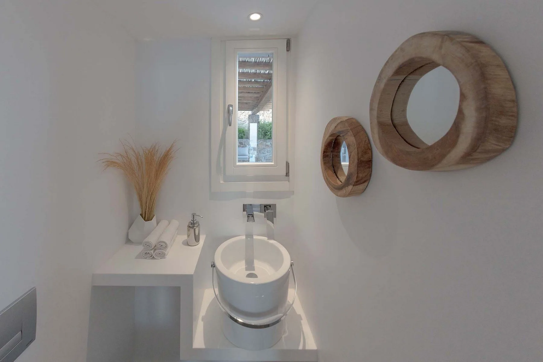 A bright bathroom with a vessel sink beneath a narrow window.