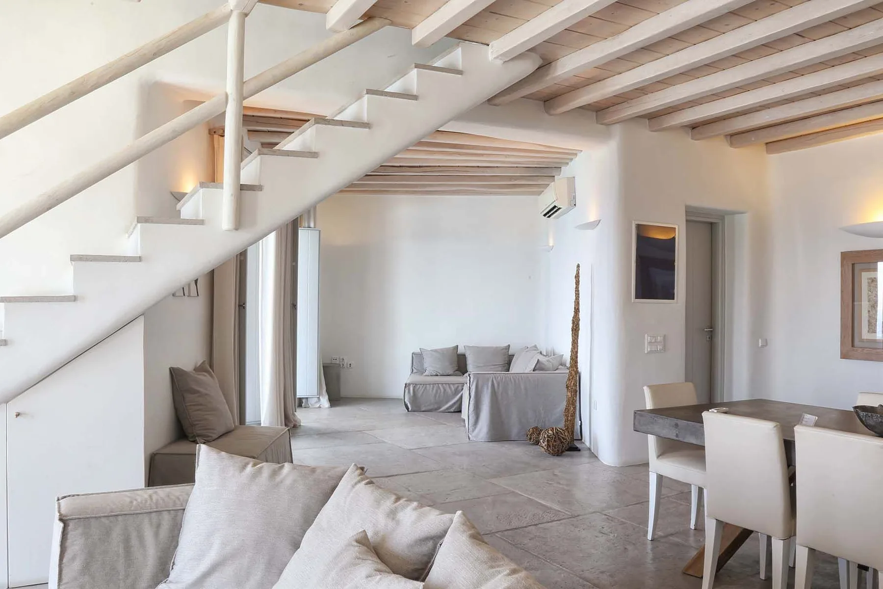 A bright living and dining area with a staircase and neutral seating.