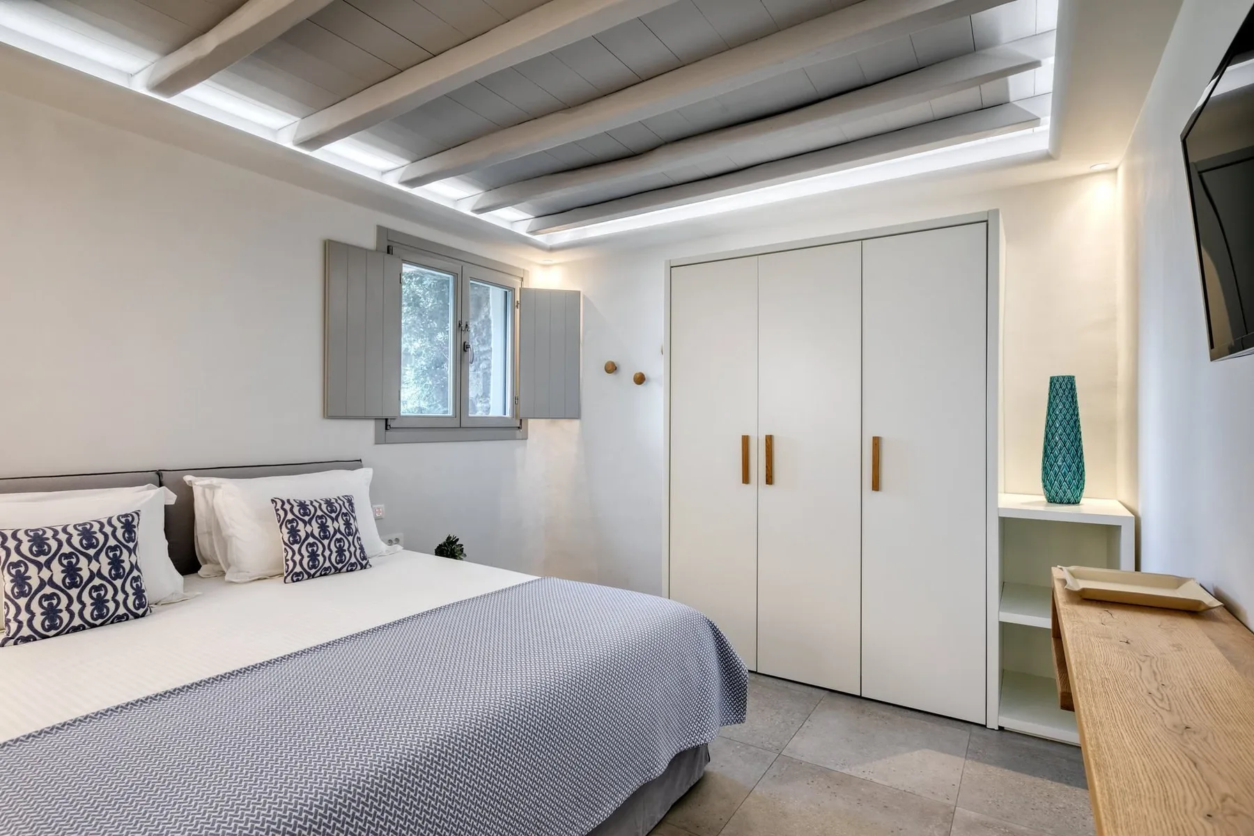 A bedroom with a double bed, a wardrobe, and a window.