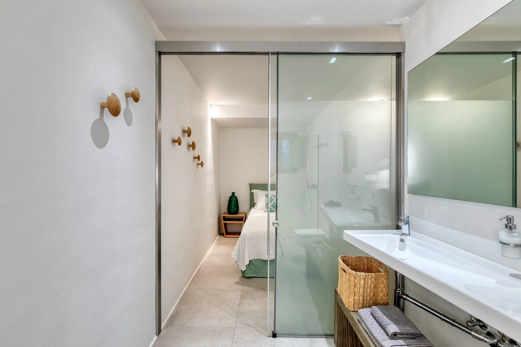 A bathroom vanity with a glass shower enclosure beside a bedroom.