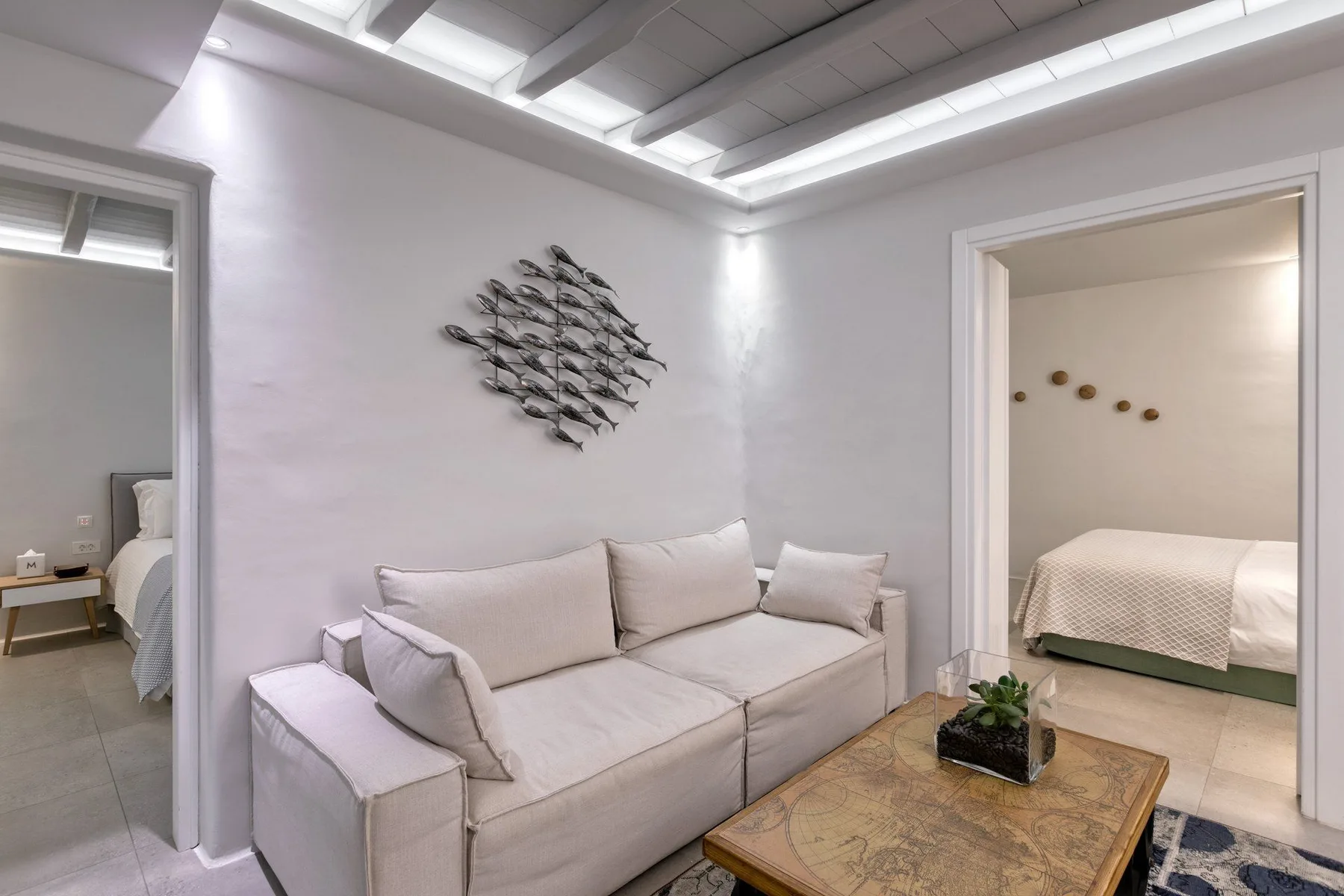 A bright sitting area with a light-colored sofa and a doorway to a bedroom.