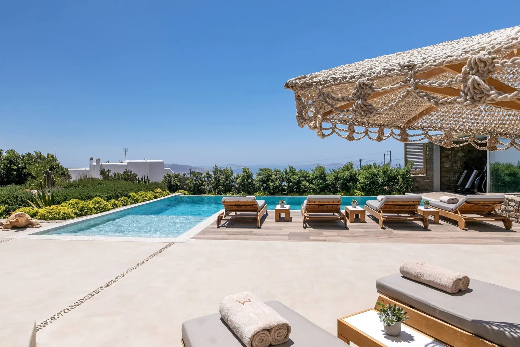 An outdoor pool and sun loungers sit beside a broad paved terrace.