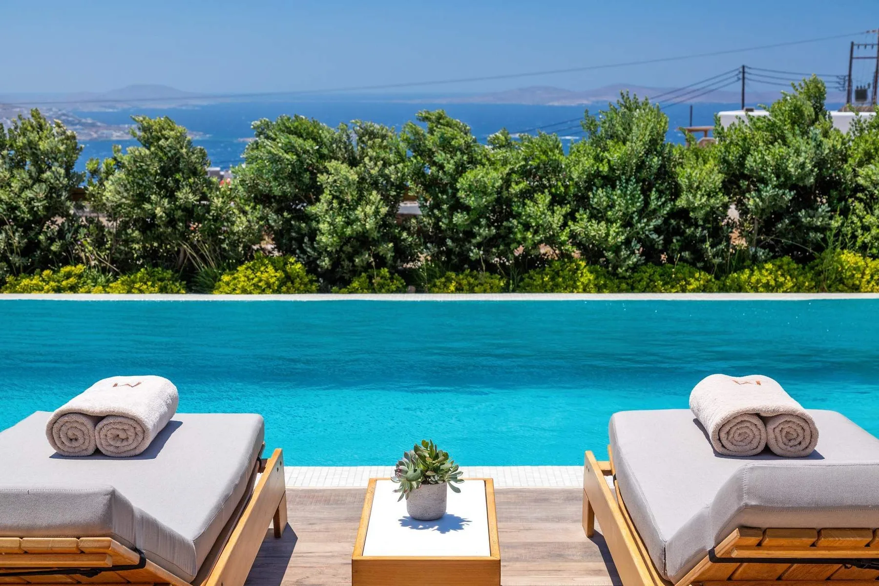 Outdoor poolside scene with two cushioned loungers and a small table.