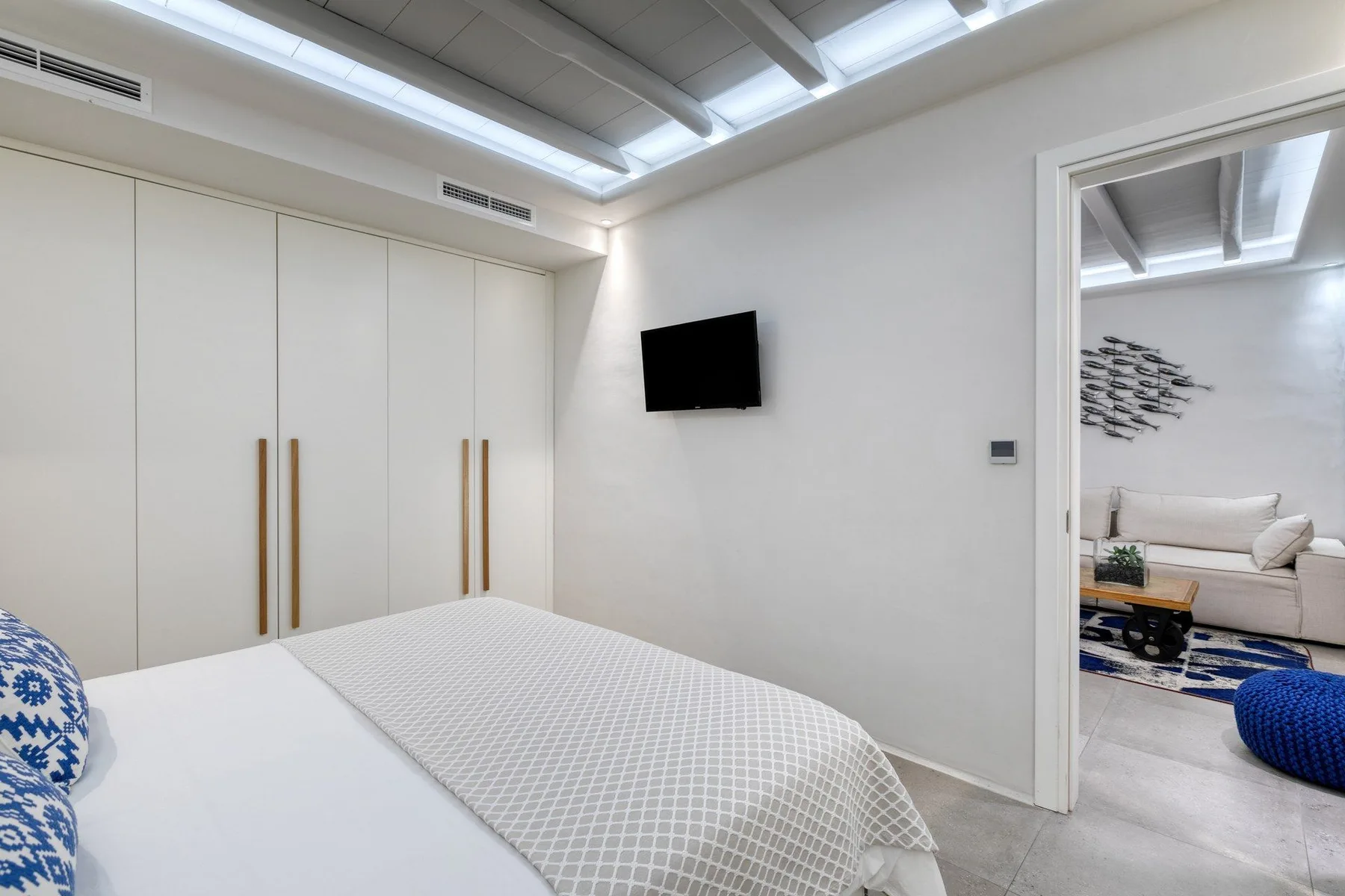 A bedroom with a bed, built-in wardrobes, and a wall-mounted television.