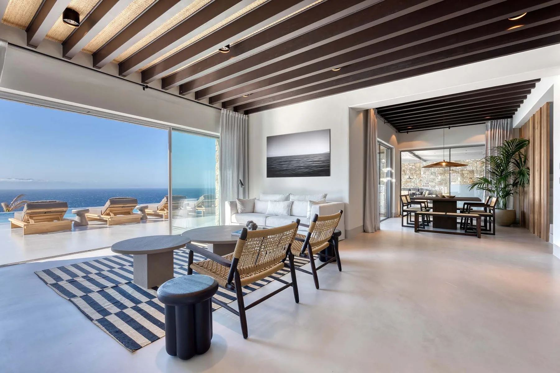 Una luminosa sala de estar se abre a una terraza con vistas al mar y asientos al aire libre.