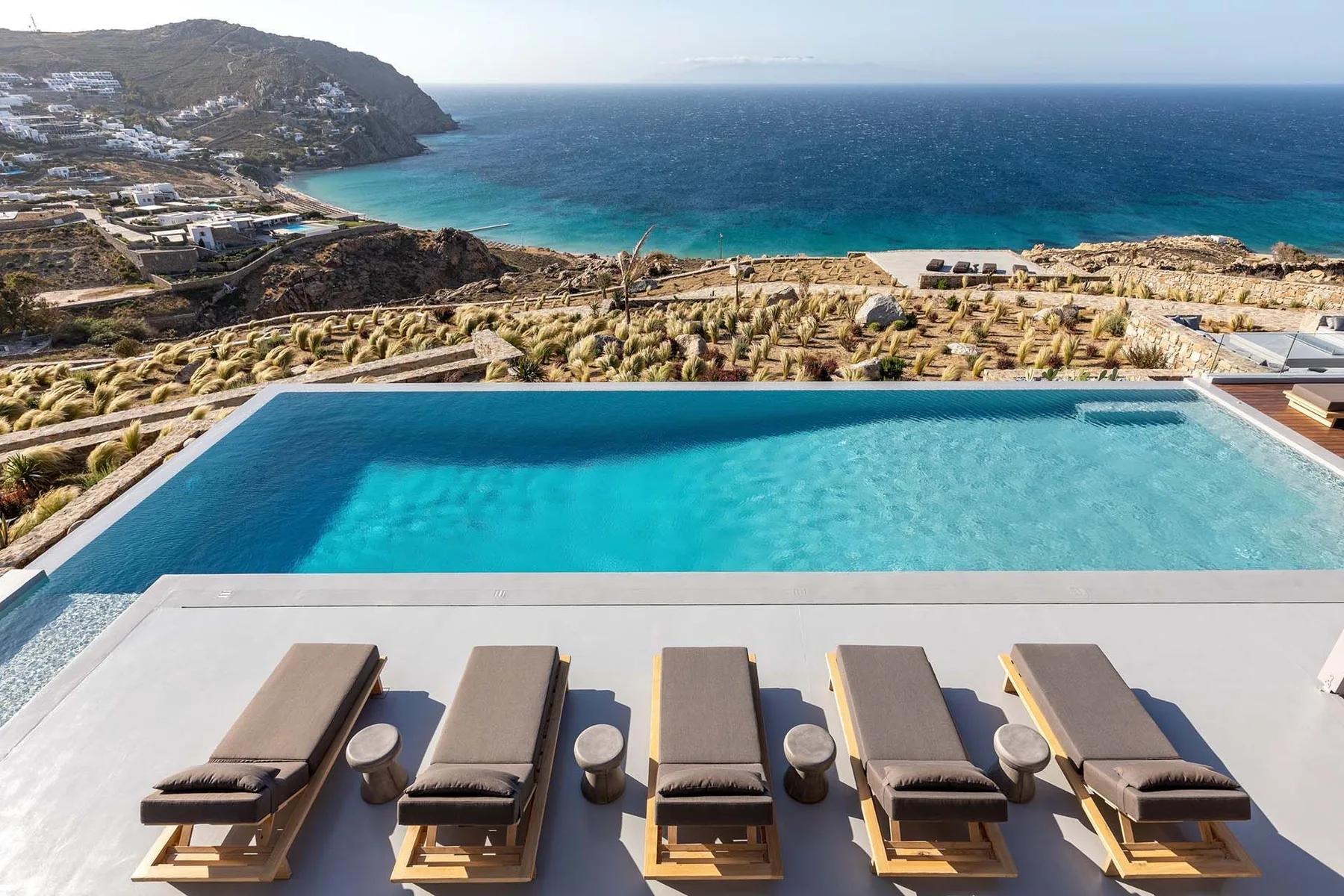 Una piscina con vistas al mar y tumbonas junto al borde.