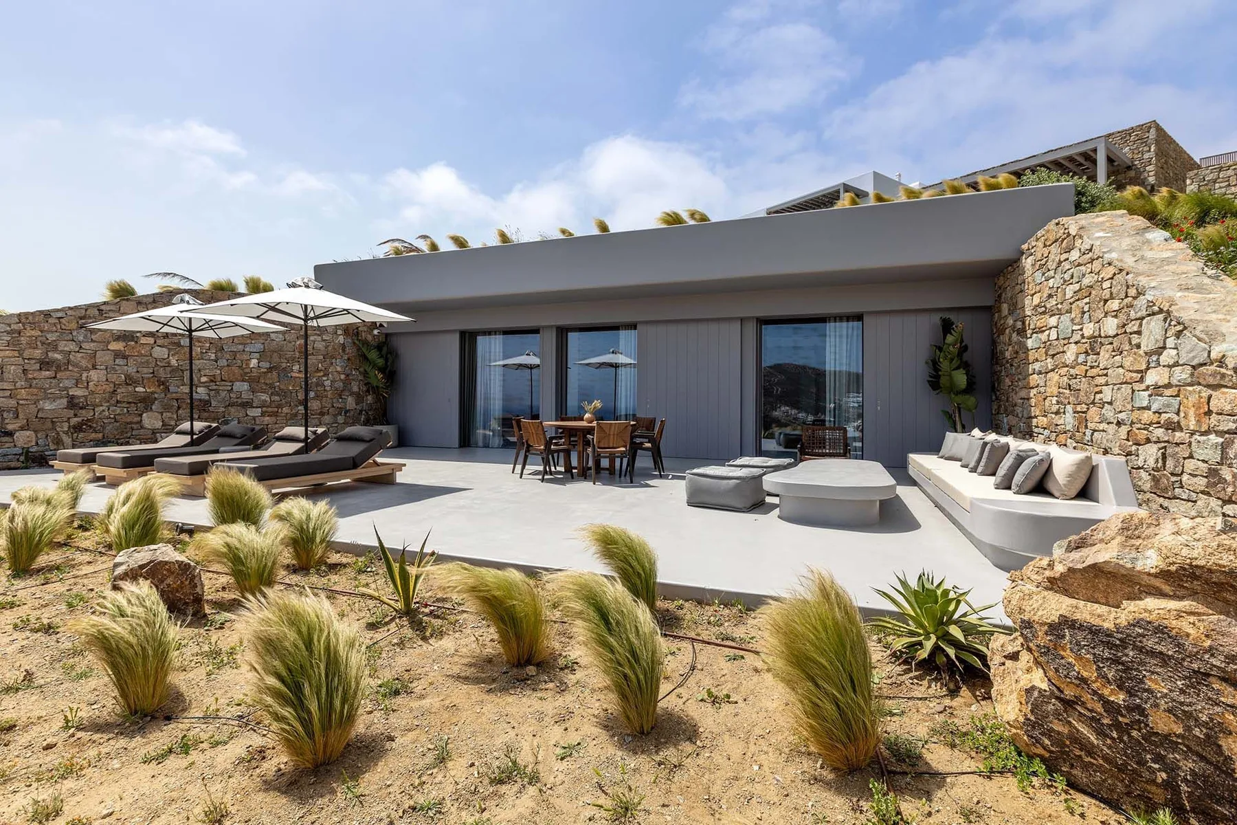 Un patio moderno con asientos al aire libre y una mesa de comedor junto a un edificio bajo.