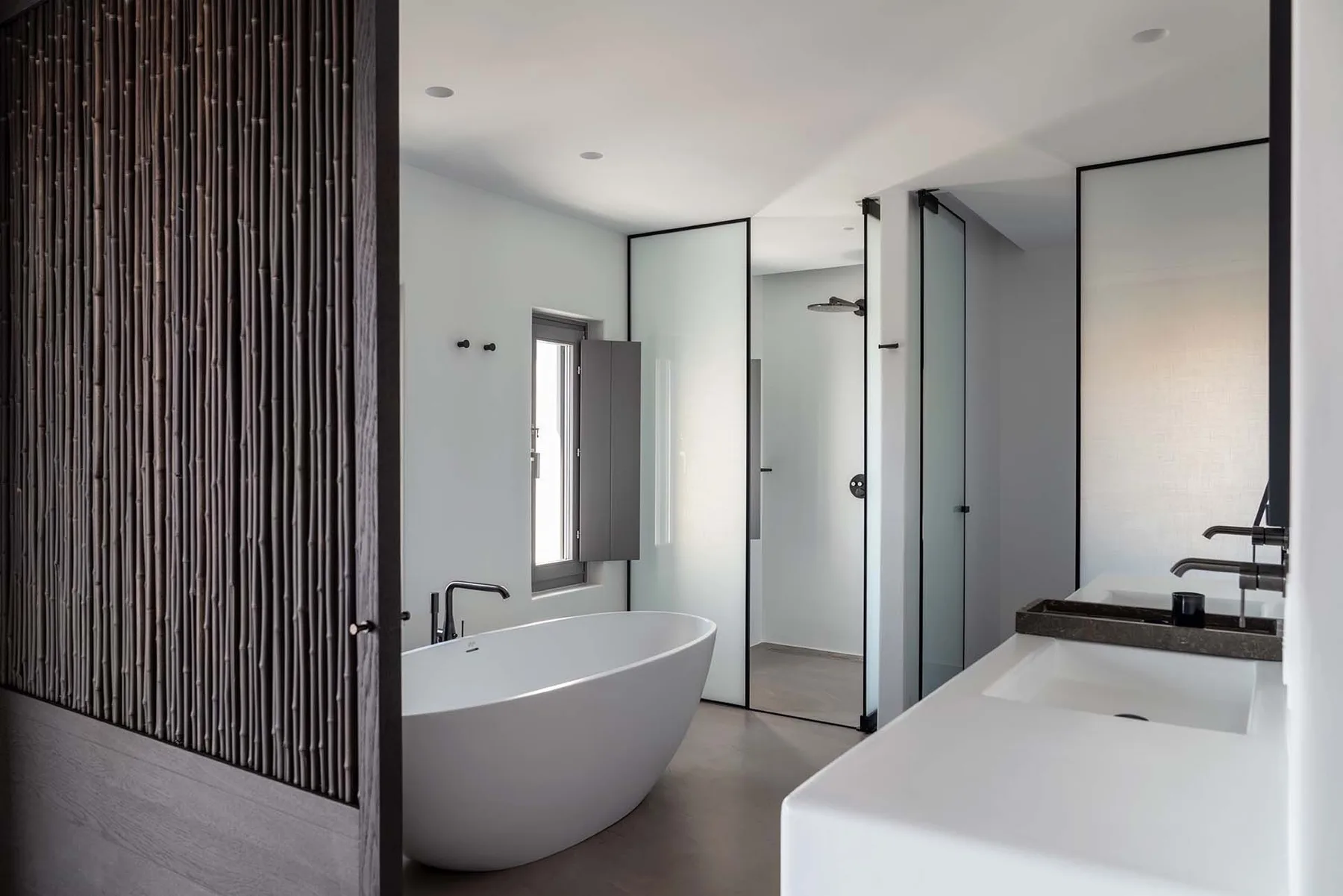 Un baño moderno con una bañera exenta y un largo mueble de lavabo blanco.