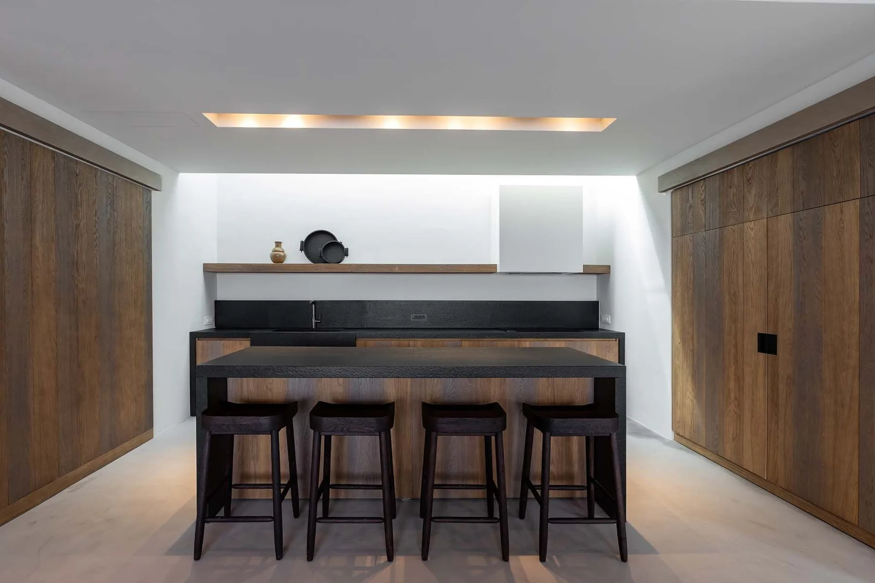 Una habitación moderna con una barra oscura y asientos entre paredes altas revestidas de madera.