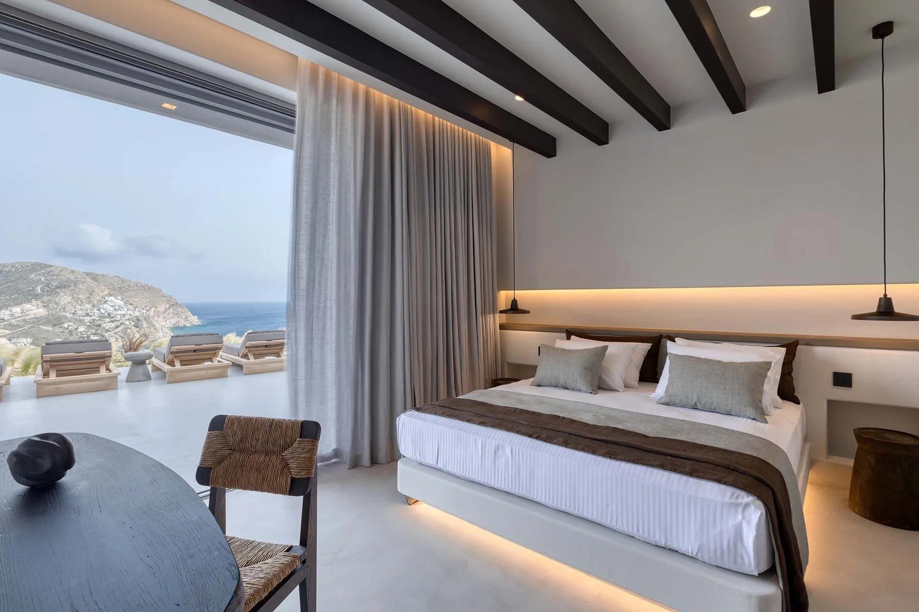 Un dormitorio con una cama grande junto a una vista abierta al mar.