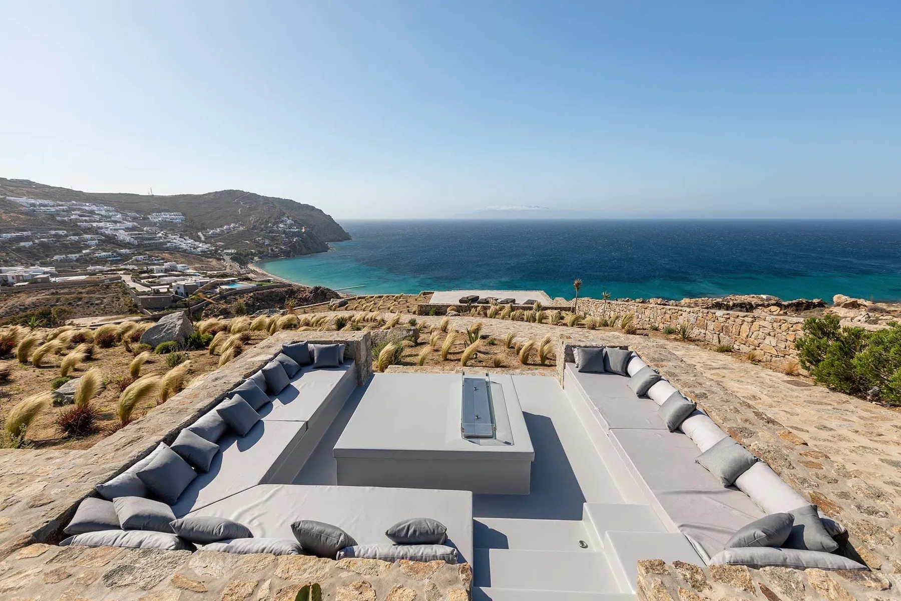 Una zona de descanso al aire libre con asientos integrados ofrece vistas al mar.