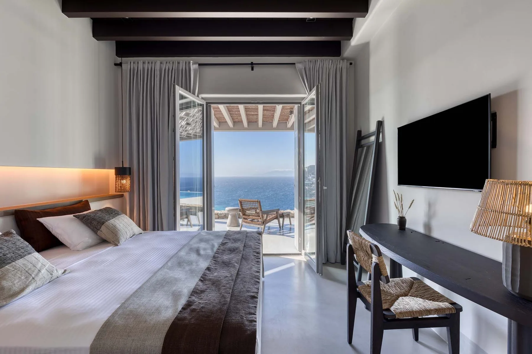 Un dormitorio da a un balcón con vistas al mar.