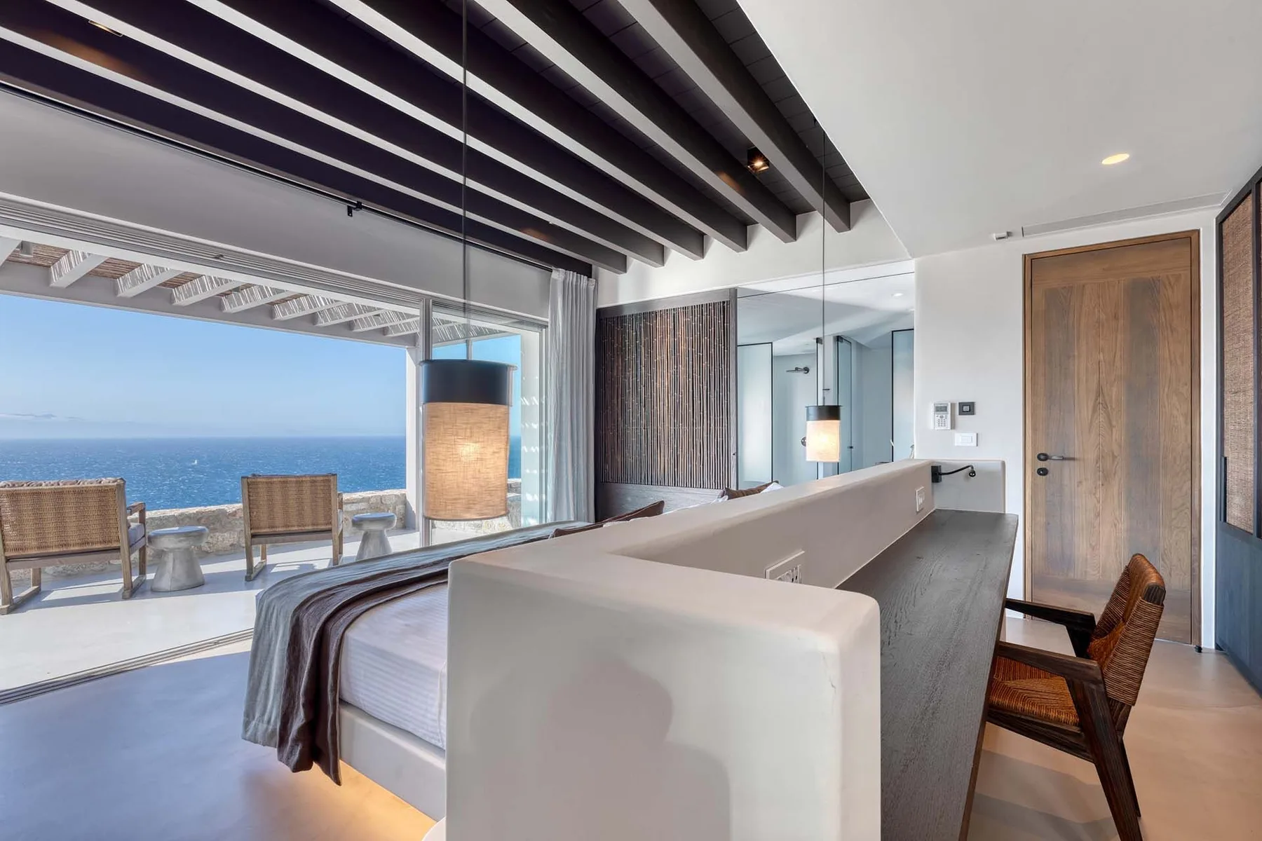 Dormitorio con una cama junto a un ventanal con vistas al mar.