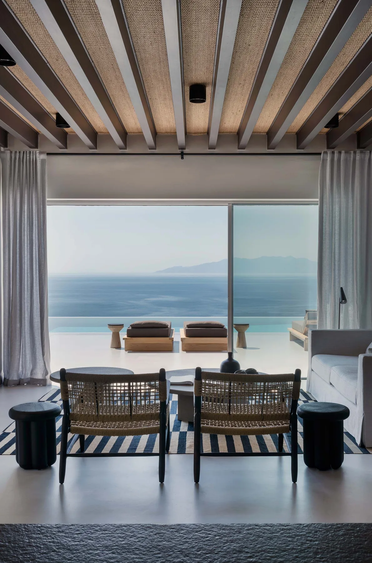 Una sala de estar se abre a una vista del mar a través de amplias puertas de vidrio.