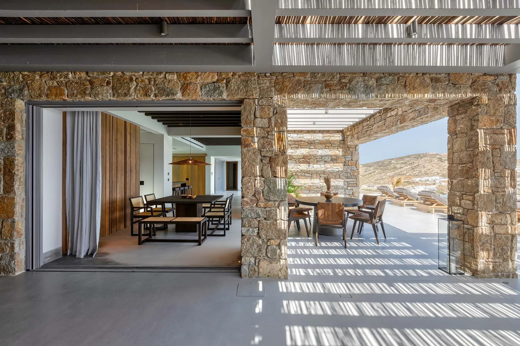 Un patio enmarcado en piedra con asientos al aire libre junto a un comedor abierto.