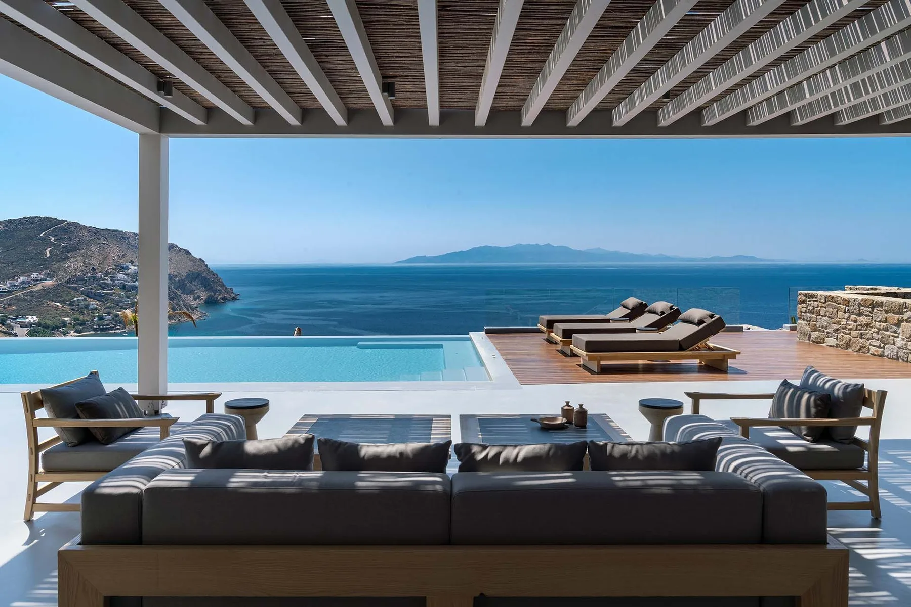 Una terraza junto al mar tiene asientos, una piscina y vistas al mar azul.