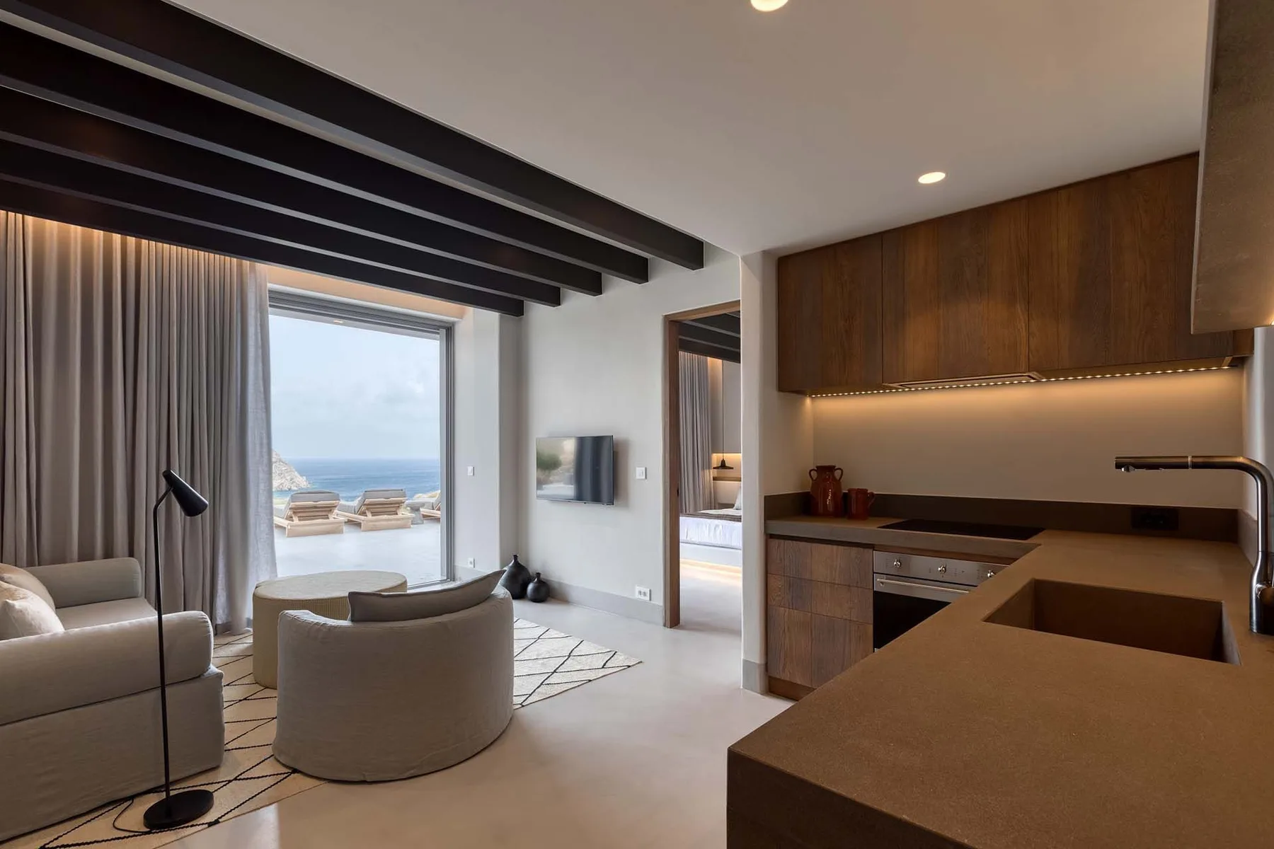 Una luminosa sala de estar da a una vista al mar, con asientos junto a una cocina compacta.