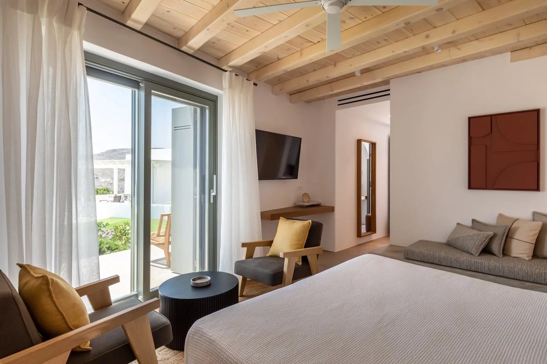 A bedroom with a bed, seating, and sliding glass doors opening to a patio.
