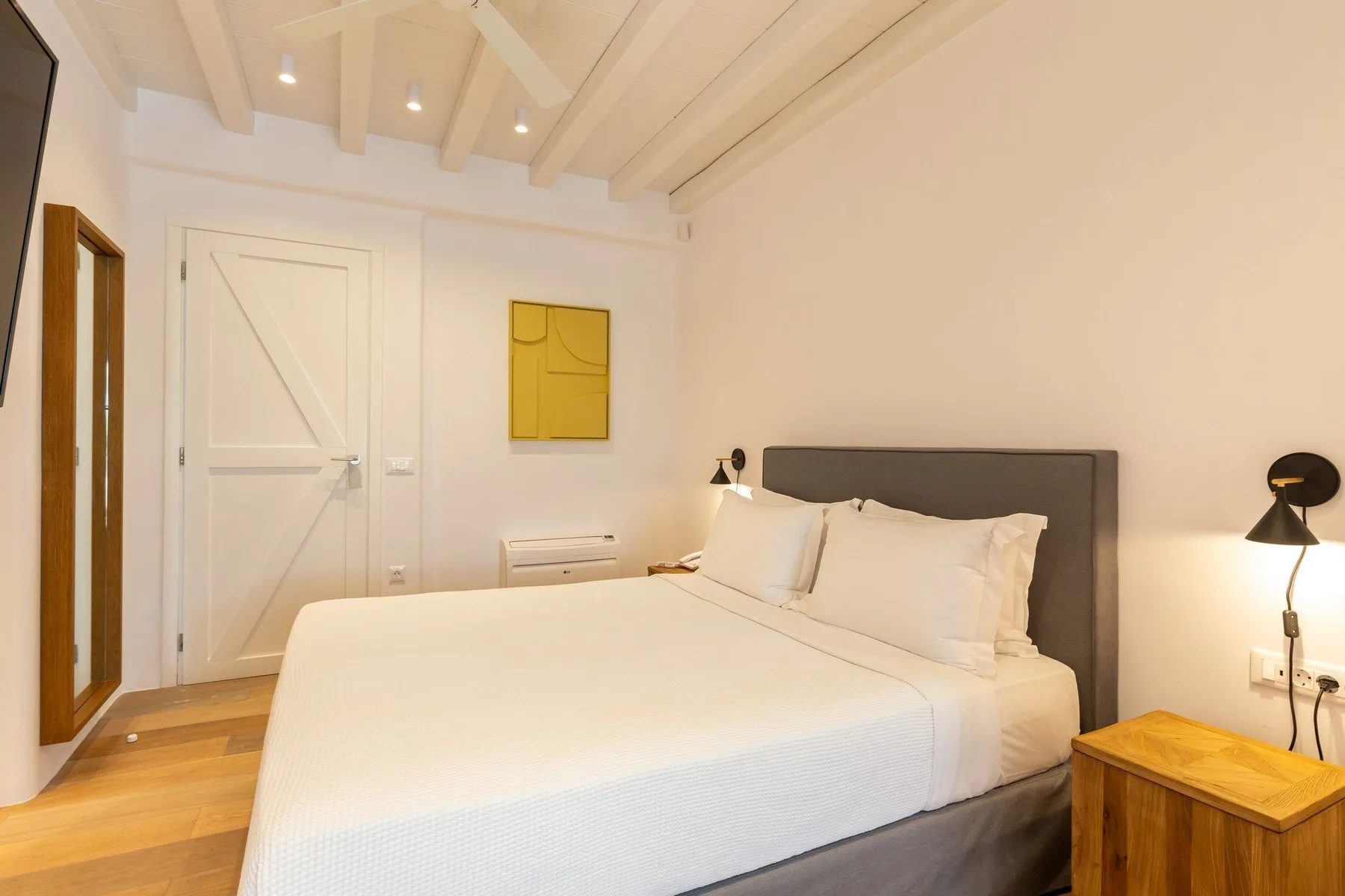 A bedroom with a large bed, gray headboard, and white bedding.