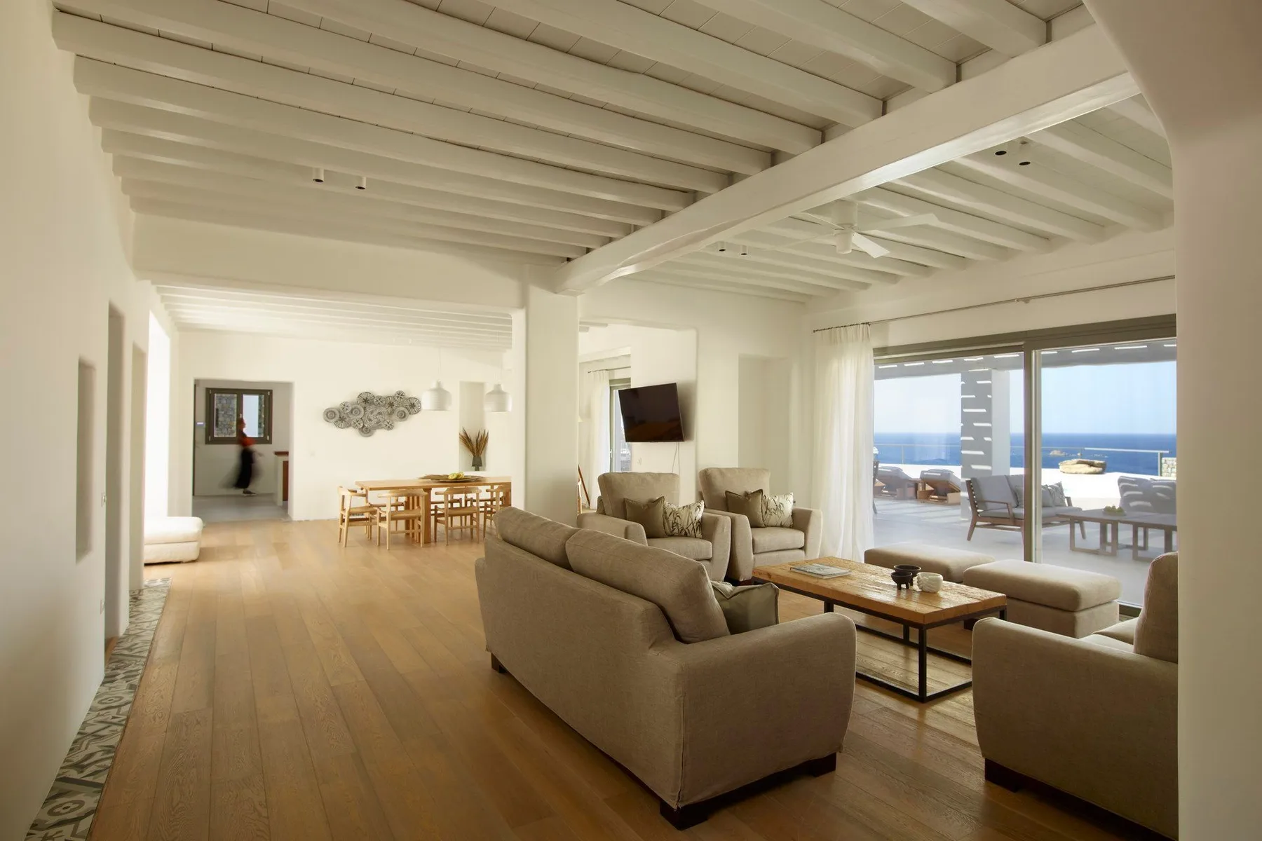 A bright living room with seating around a coffee table beside large windows.