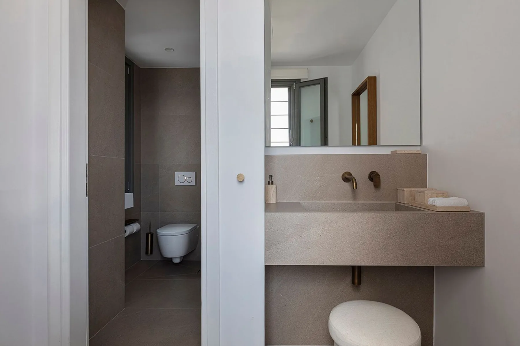 A bathroom with a wall-mounted sink and a toilet in a separate alcove.