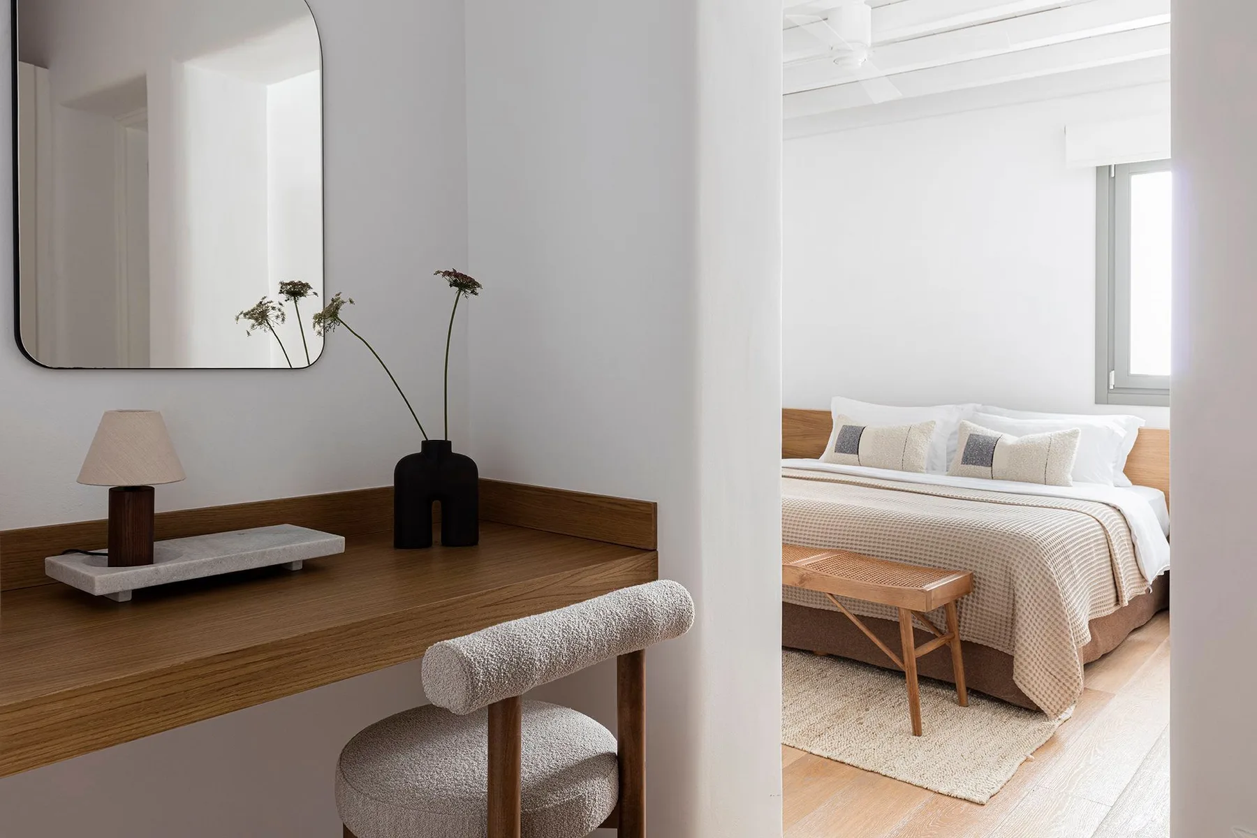 A bedroom with a neatly made bed, visible through an open doorway.