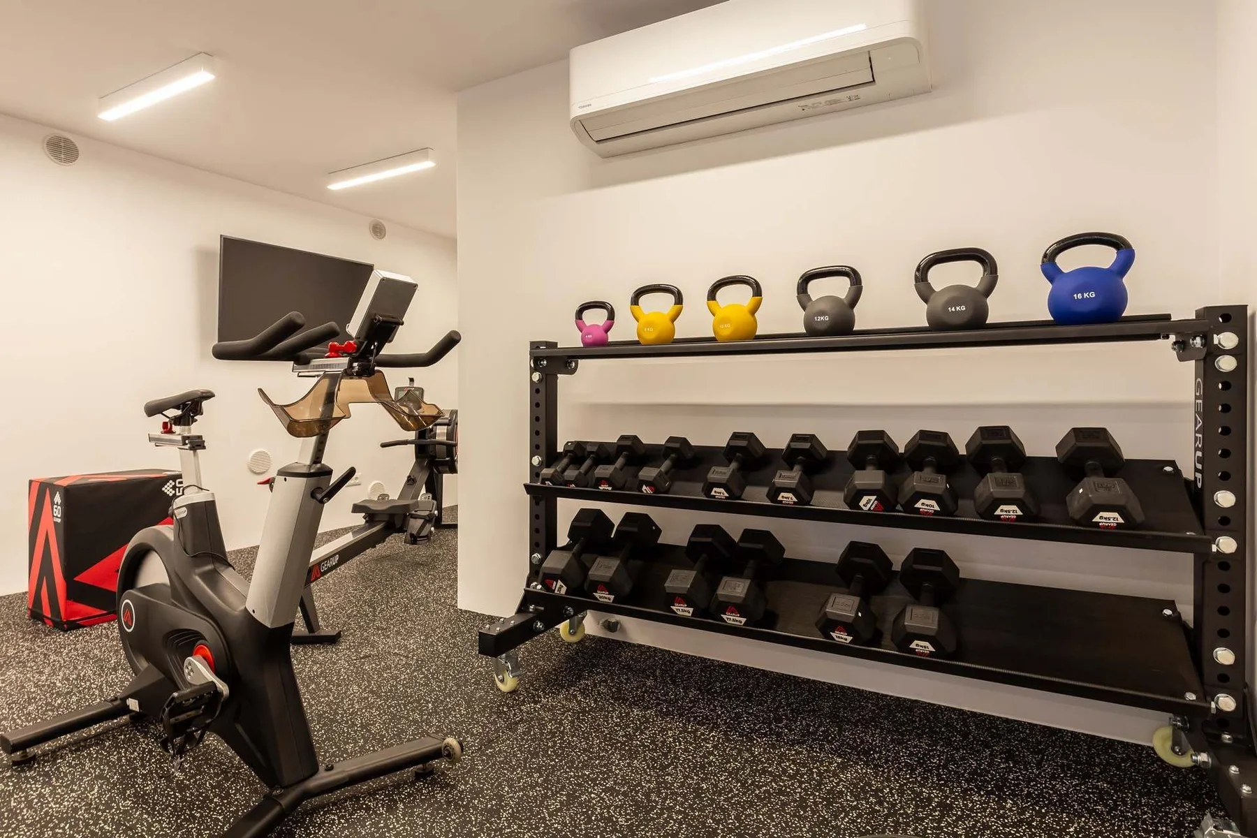 A fitness room with exercise bikes and racks of weights.