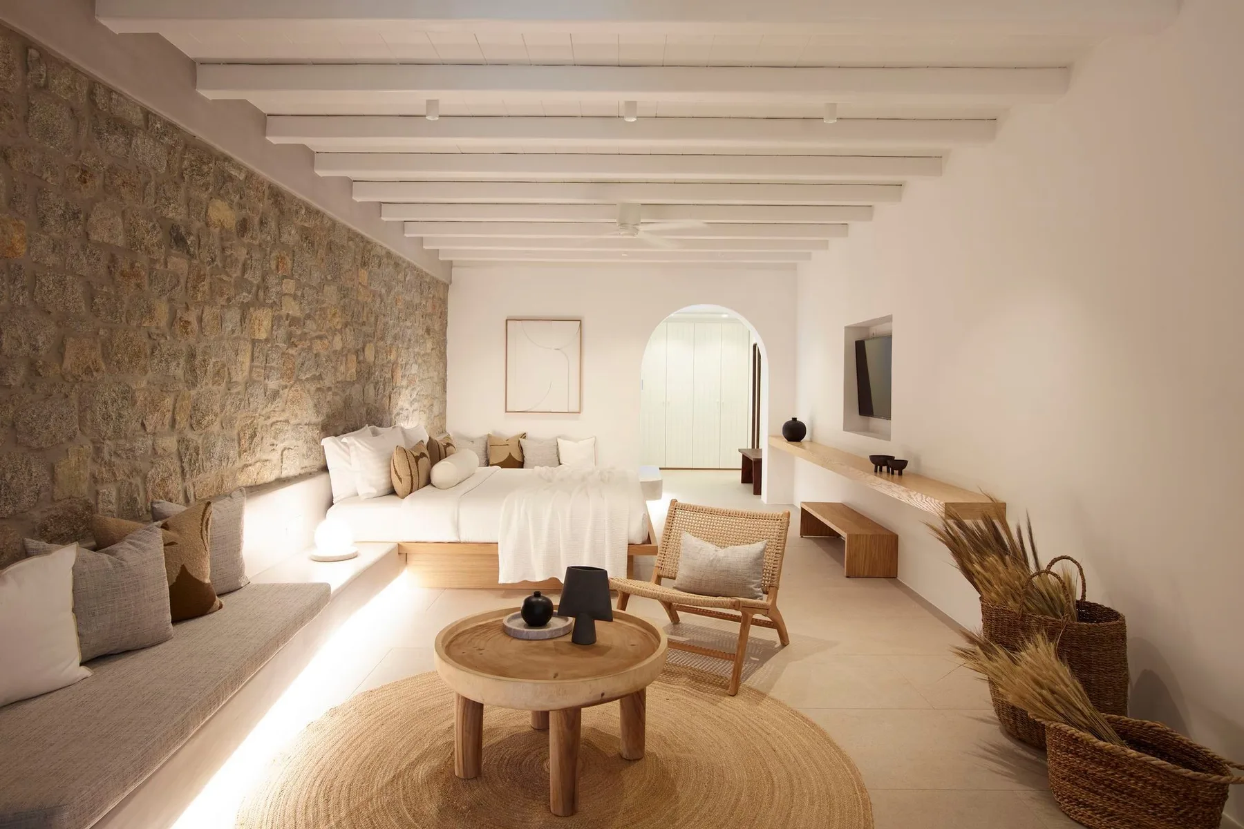 A bright living room has a seating area beside a white bed.