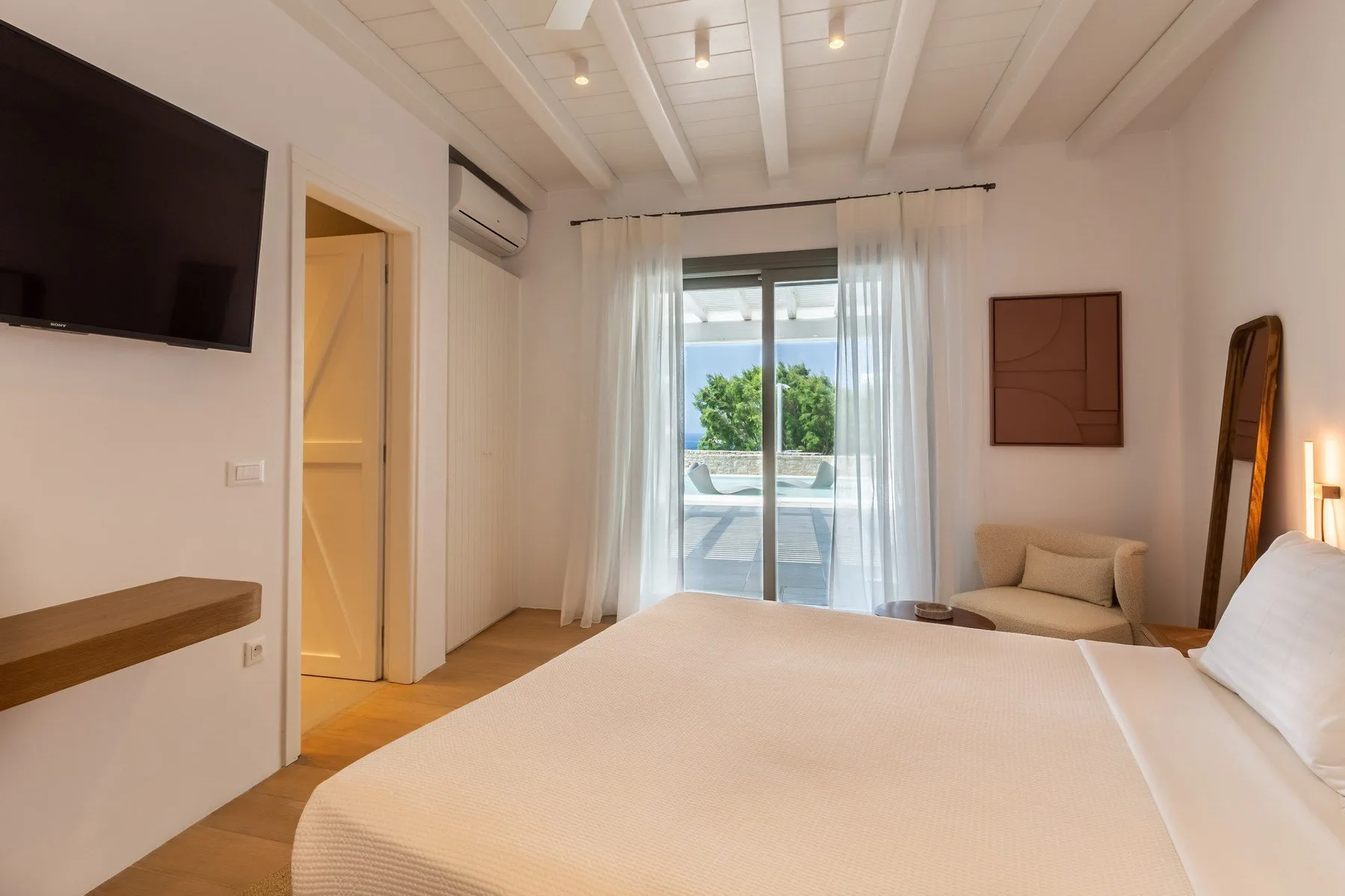 A bright bedroom with a large bed and glass doors opening to a patio.