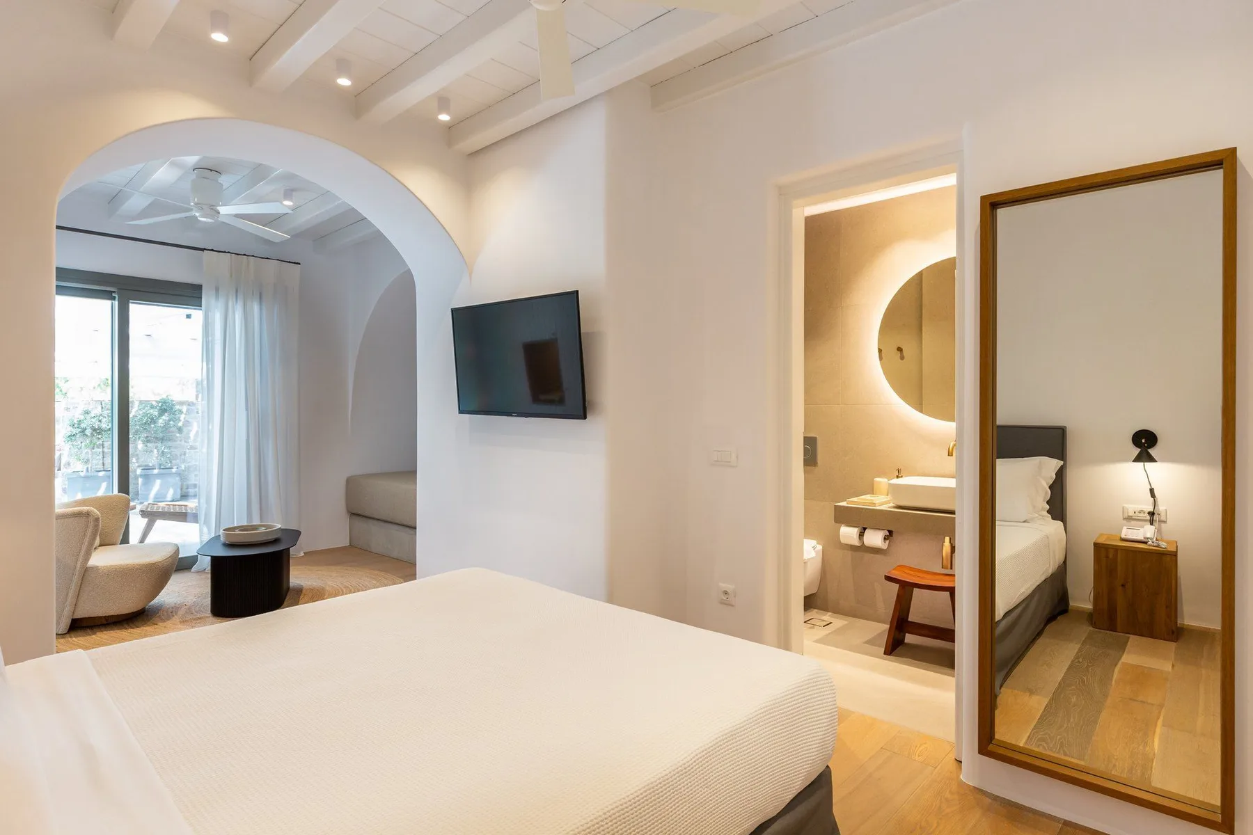 A bedroom with a bed, television, and an arched opening to a sitting area.