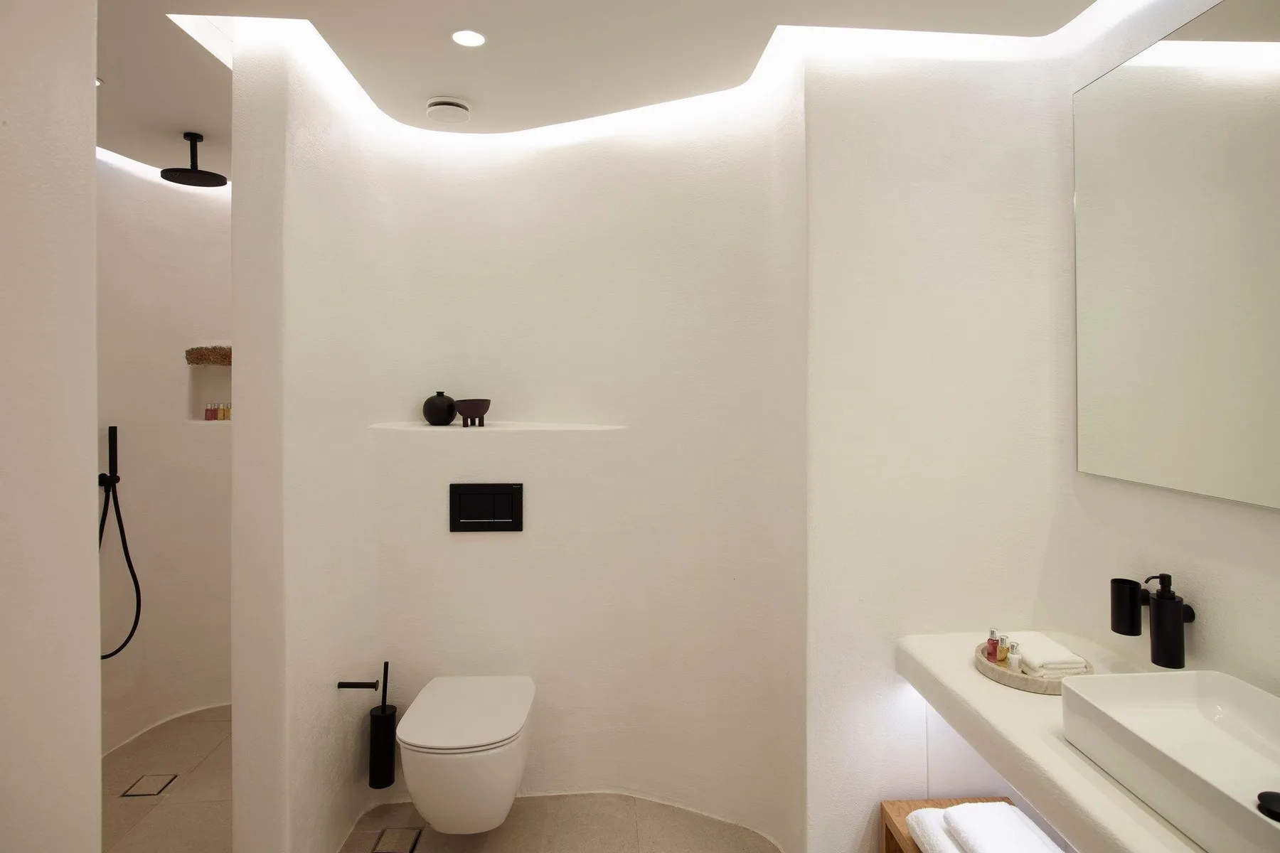 A modern bathroom with a toilet, shower, and sink.