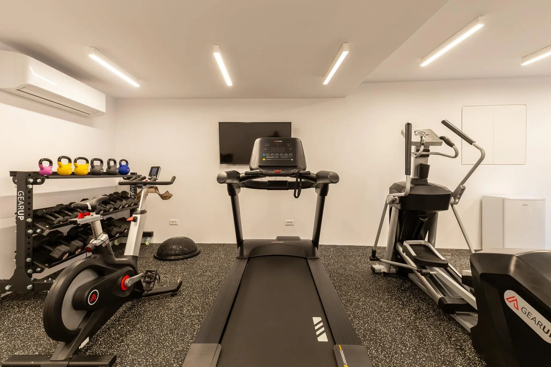 A gym with treadmills, weight racks, and exercise equipment.