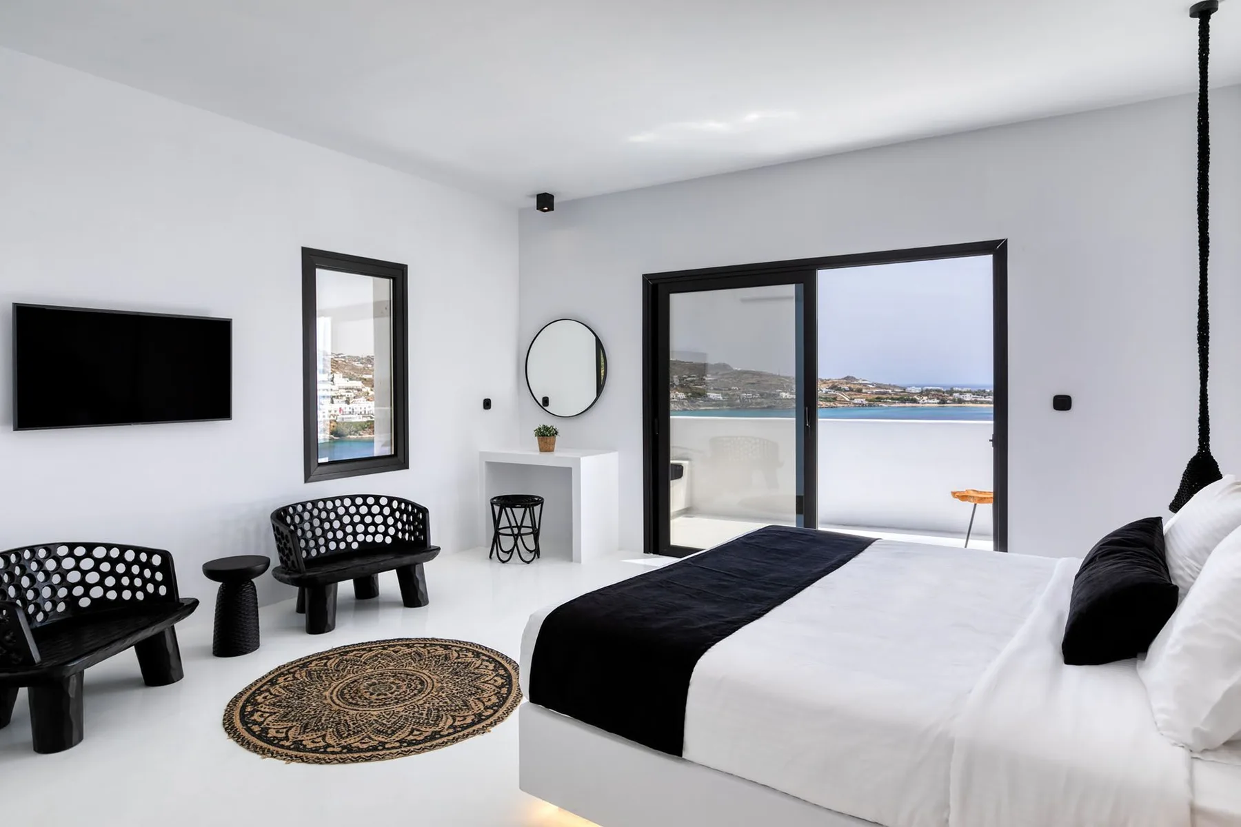 Bright bedroom with a large bed, black bedding, and sliding glass doors overlooking the water.