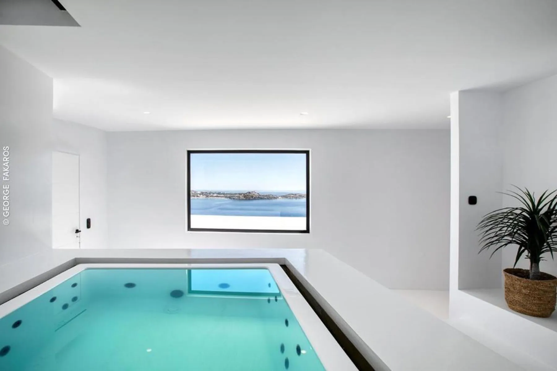 An indoor pool sits beneath a large window overlooking the water.