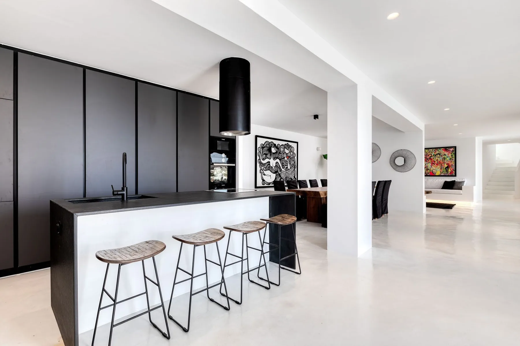 A modern open-plan kitchen with a long island and bar stools.