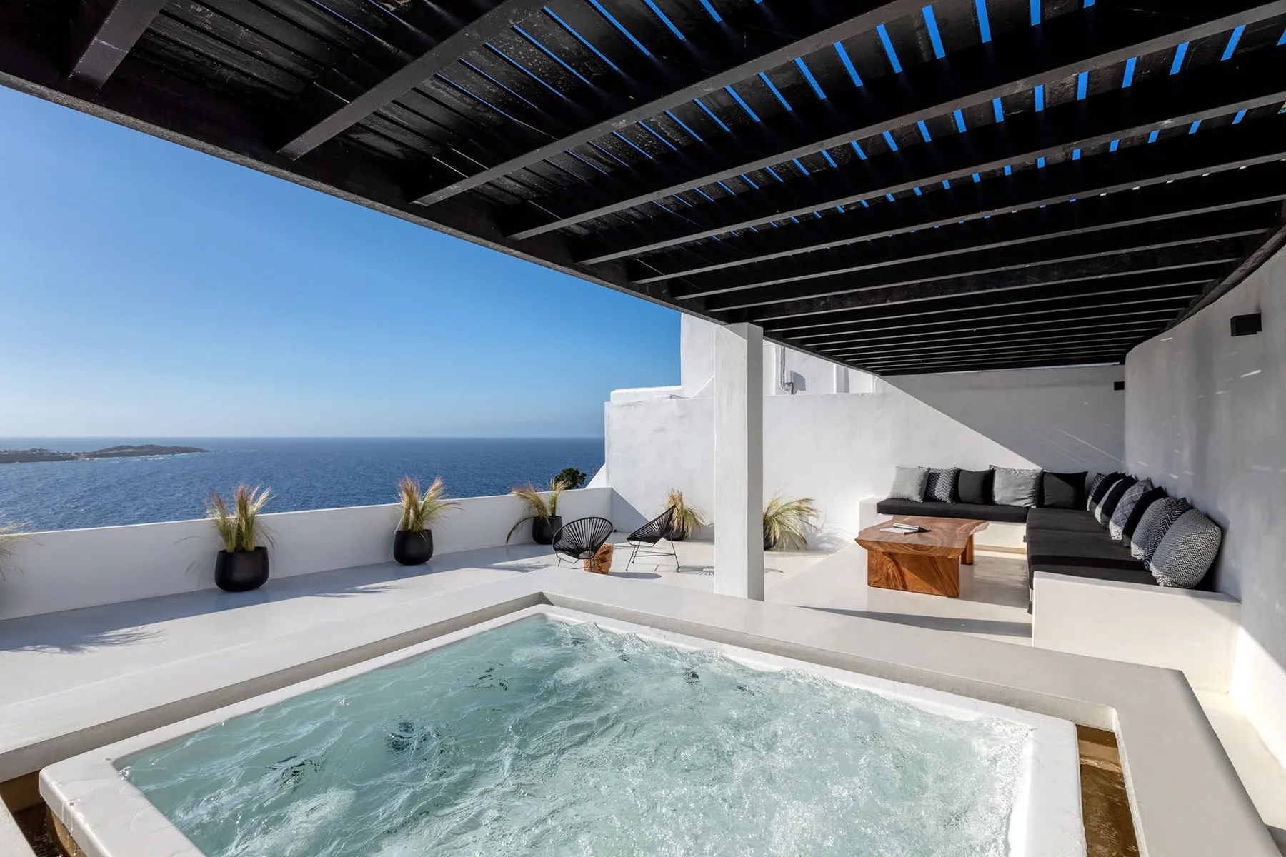 A rooftop terrace with a bubbling pool, outdoor seating, and ocean views.