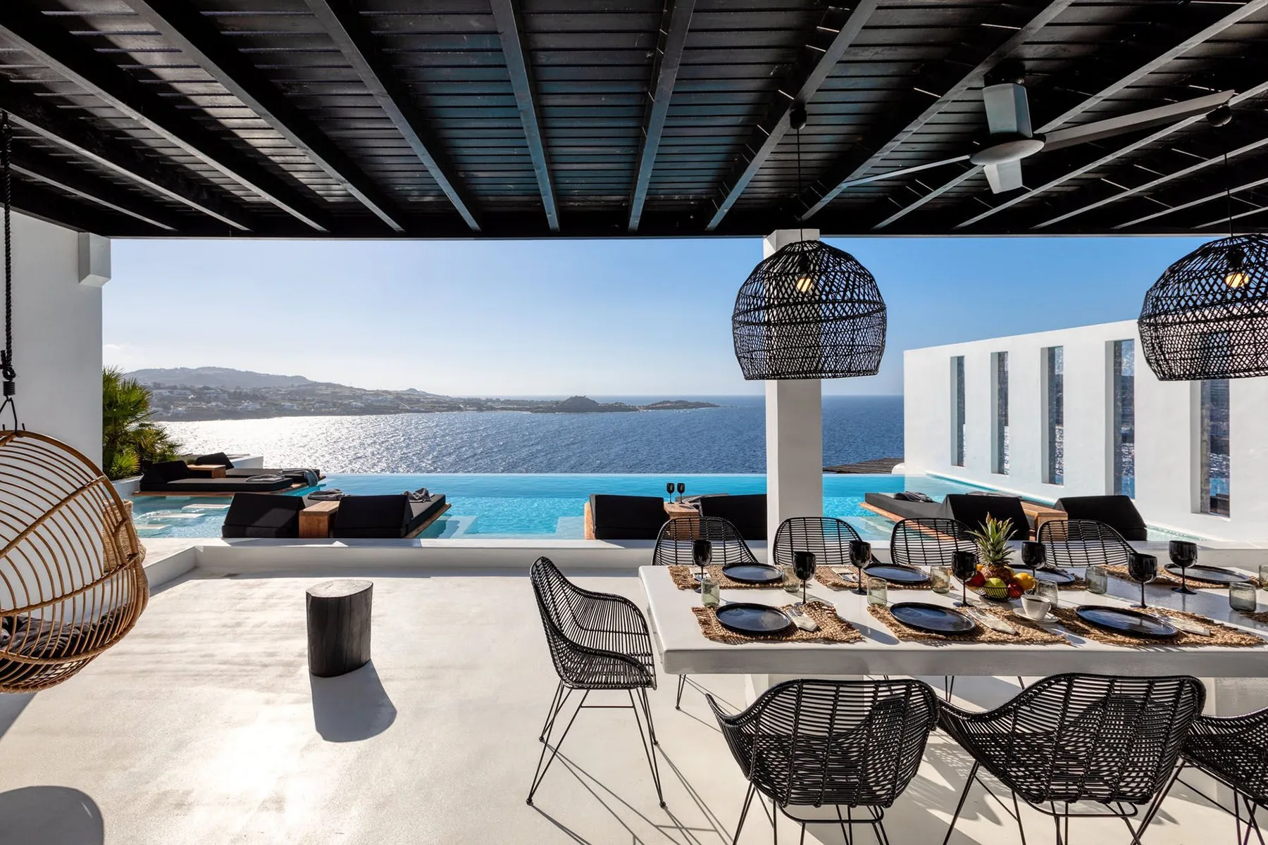 An outdoor dining terrace overlooks a pool and the sea.