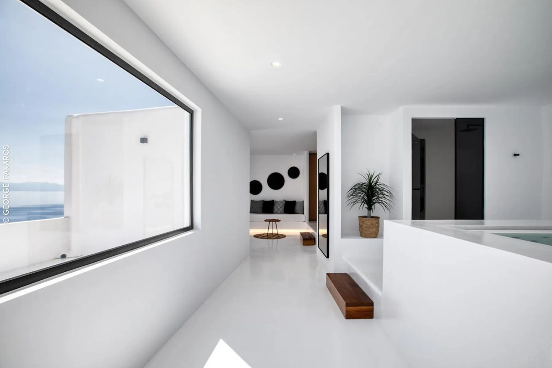 A bright modern hallway opens toward a living area with wall art and seating.