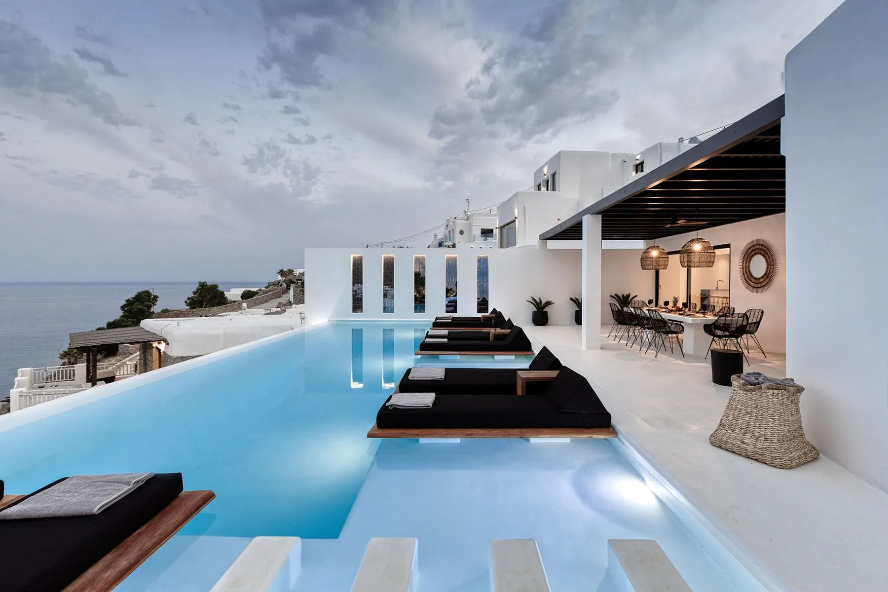 A rooftop pool beside a covered outdoor dining area overlooks the sea.