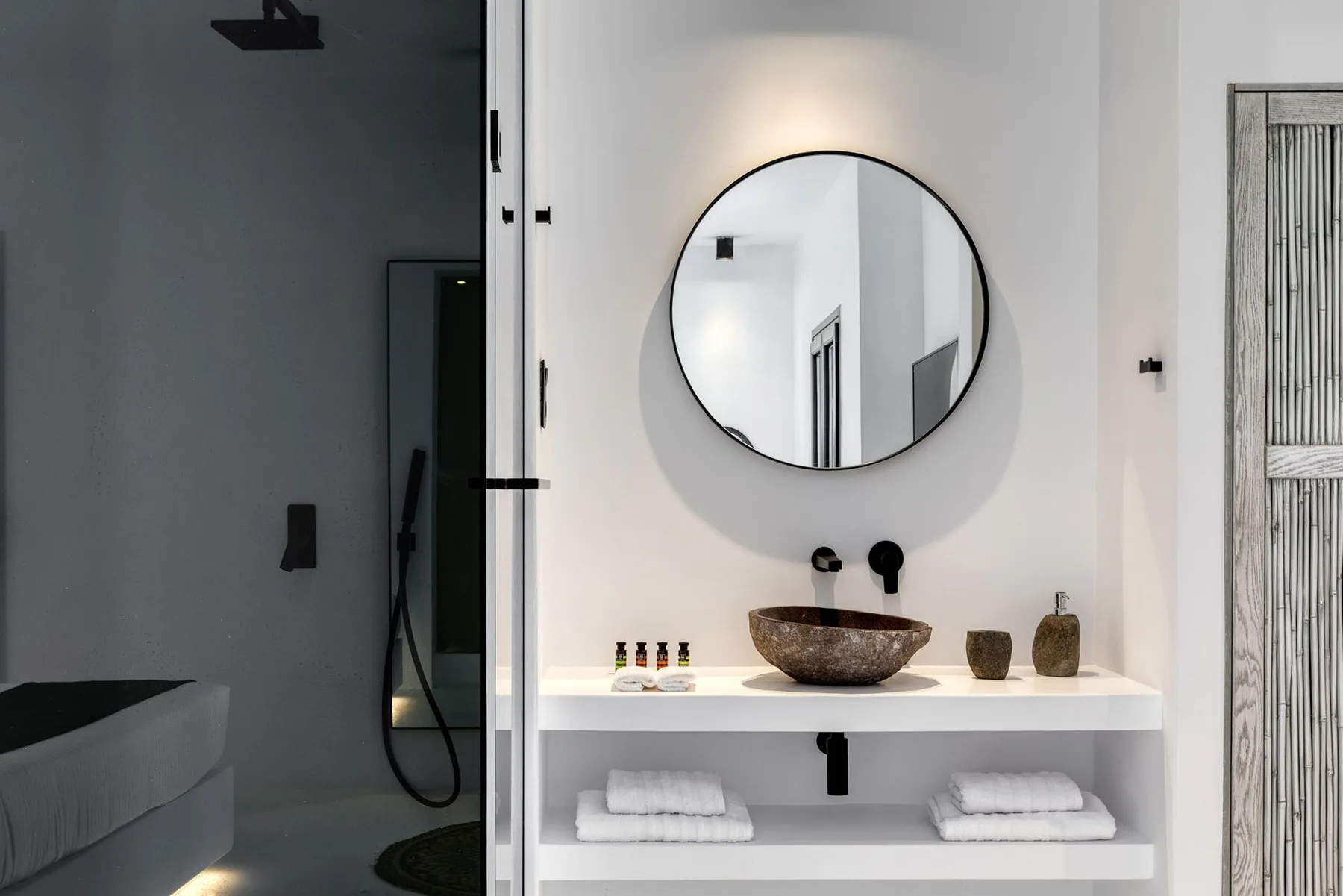 A bathroom vanity with a round mirror, basin, and folded towels.