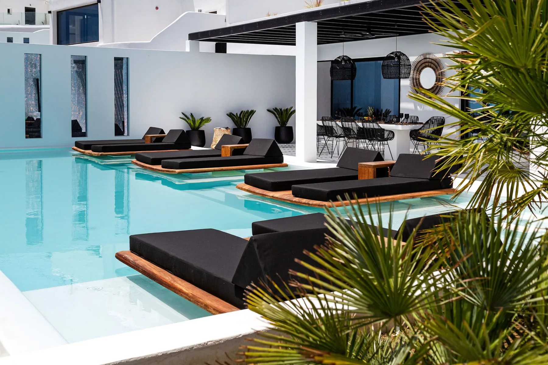 A swimming pool with dark lounge seating and a shaded dining area.