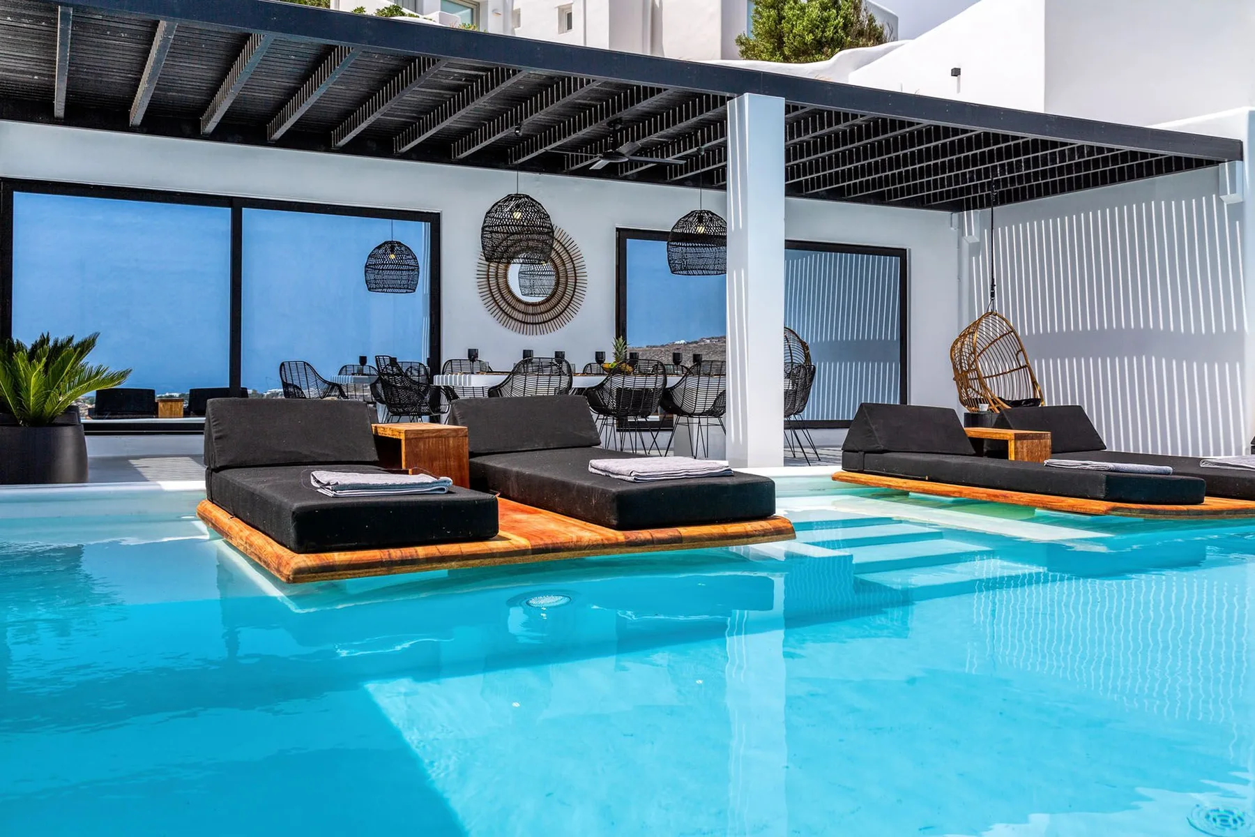 A swimming pool with lounge seating beneath a shaded patio.