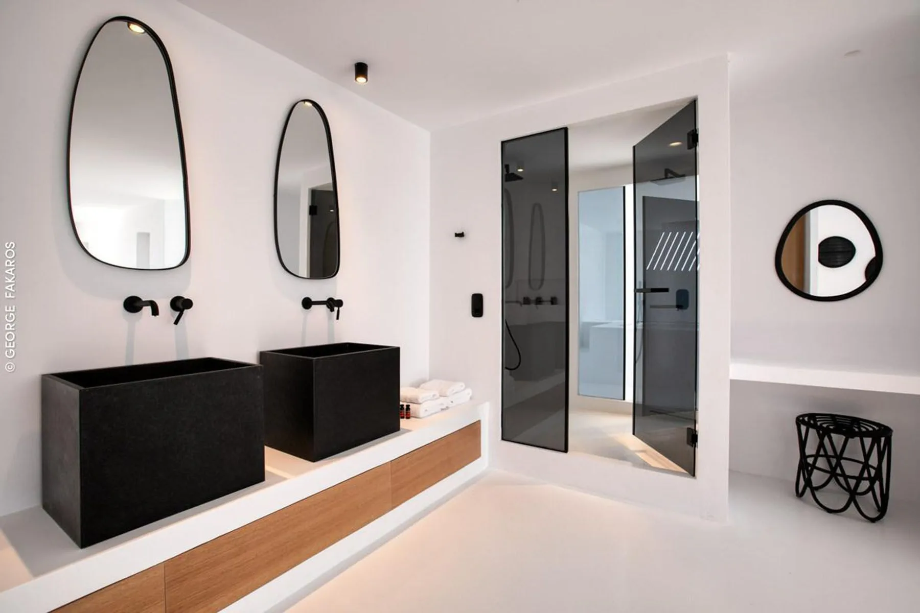 A modern bathroom with black sinks, wall mirrors, and a glass shower.