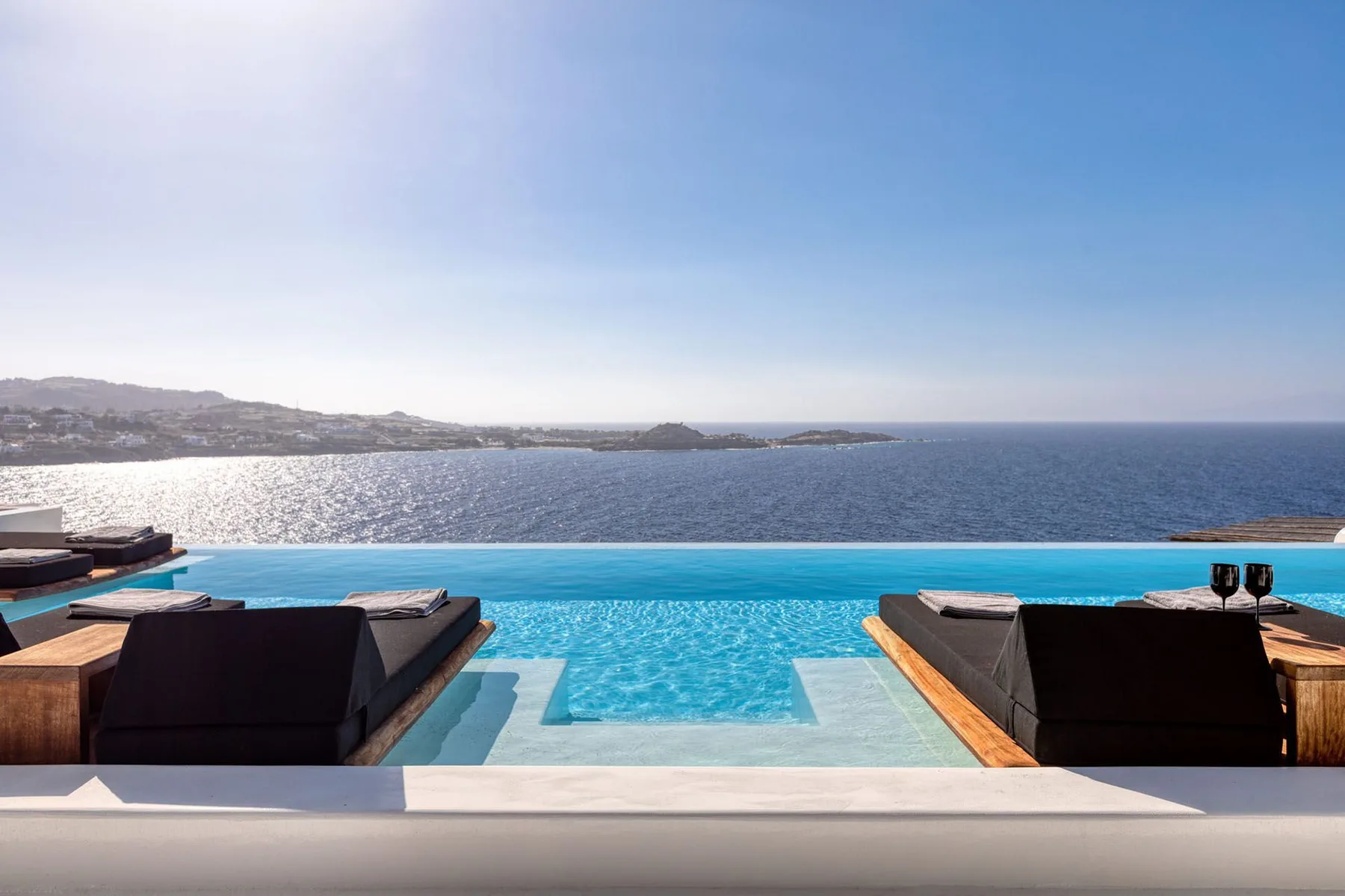 An infinity pool overlooks the sea, with loungers arranged along its edge.