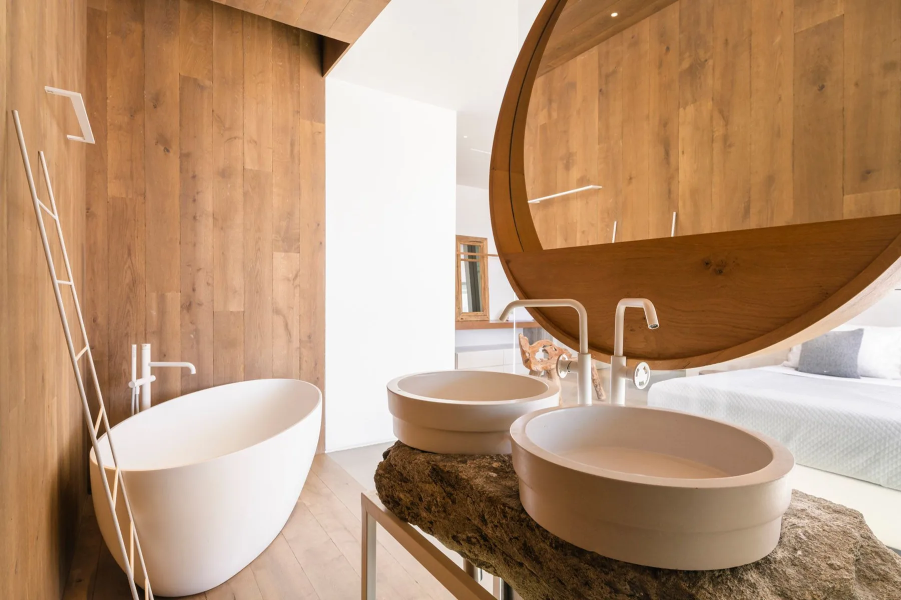 A modern bathroom features a freestanding bathtub and two round basins.