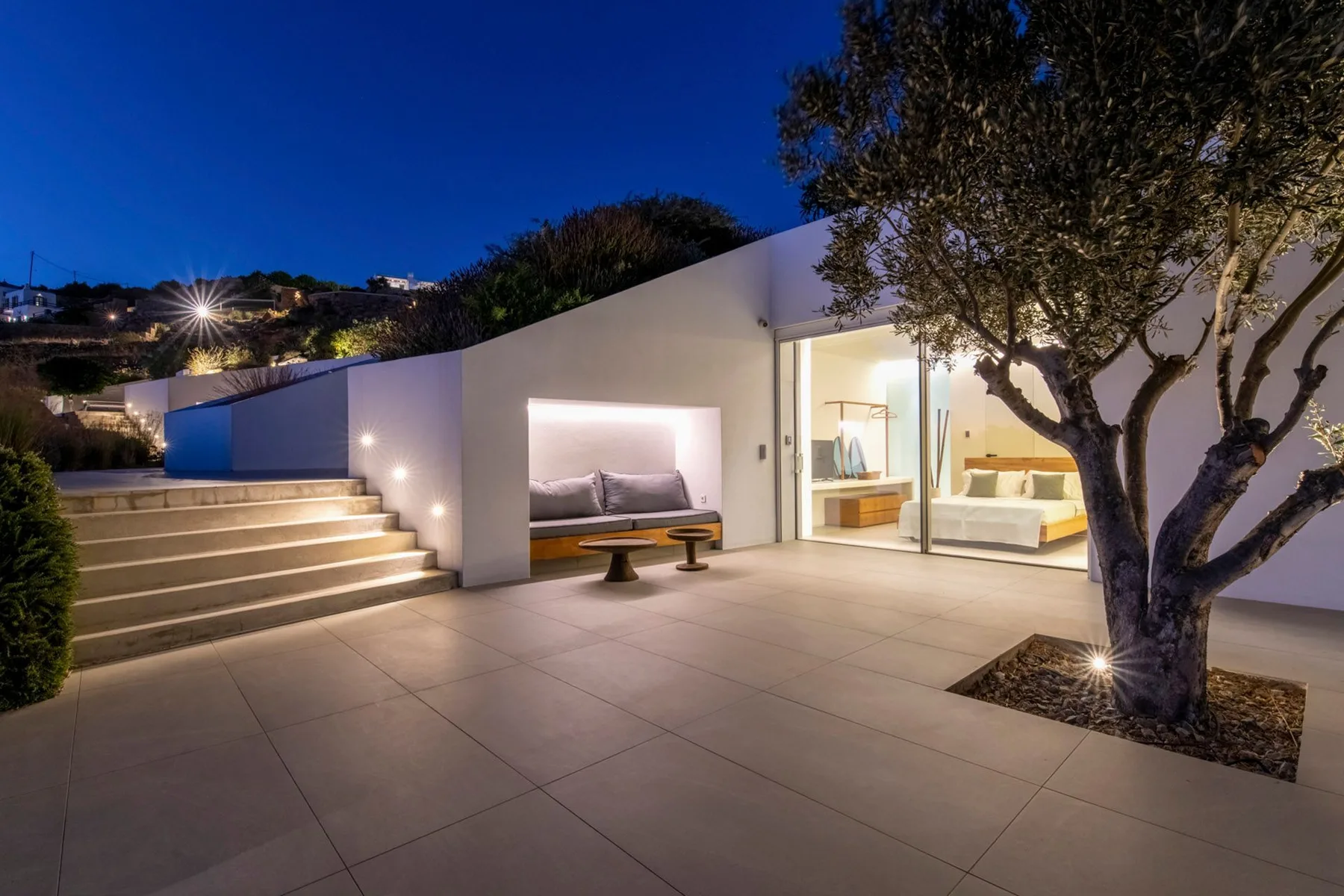 A modern outdoor patio with a lit seating nook and steps beside the building.