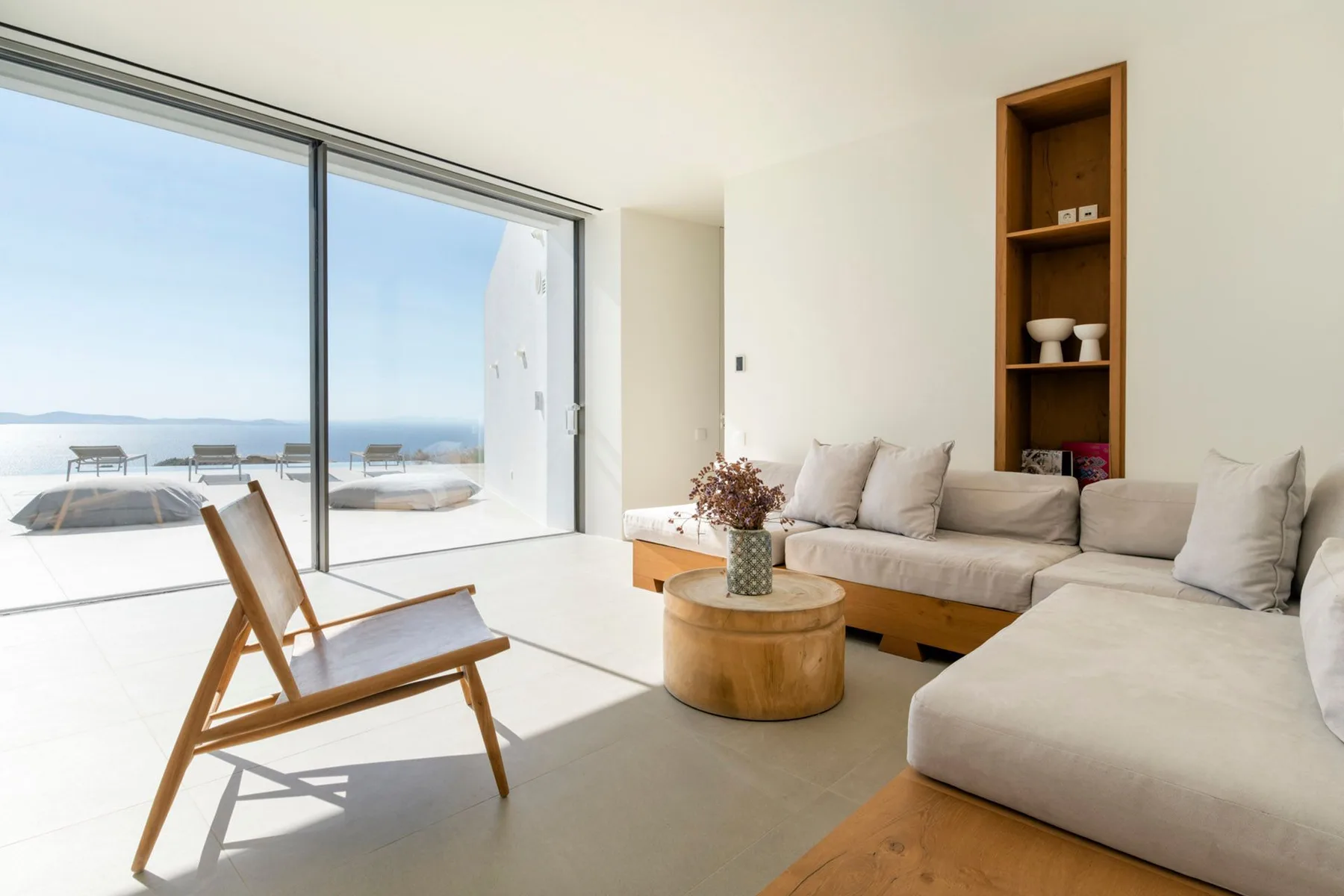 A bright living room has a large window, seating, and a round coffee table.